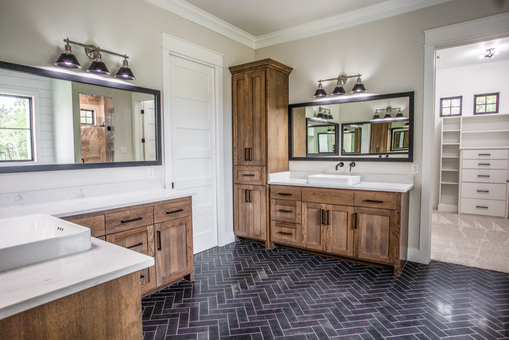 Phòng tắm phong cách đồng quê rộng rãi với gam màu trắng, be và nội thất gỗ cùng sàn nhà lát gạch tối màu theo kiểu xương cá.