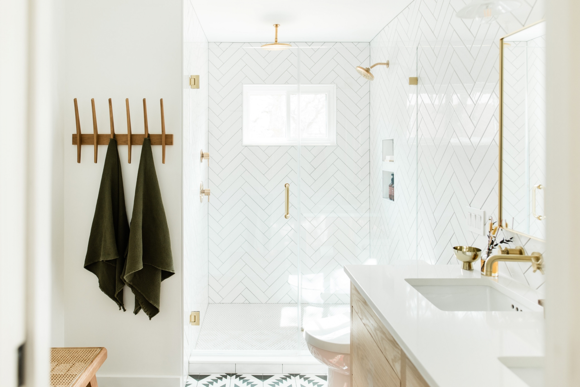 Phòng tắm sử dụng gam màu trắng chủ đạo với gạch ốp tường họa tiết xương cá sáng bóng, kết hợp vật liệu đồng thau càng tăng thêm độ lấp lánh.
