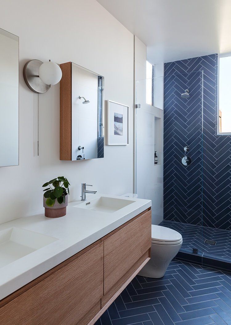 Nếu 2 phòng tắm trên chỉ ứng dụng gạch xương cá để ốp tường hoặc lát sàn thì phòng tắm này tạo nên một “dòng chảy” màu xanh lam đậm từ tường đến sàn.