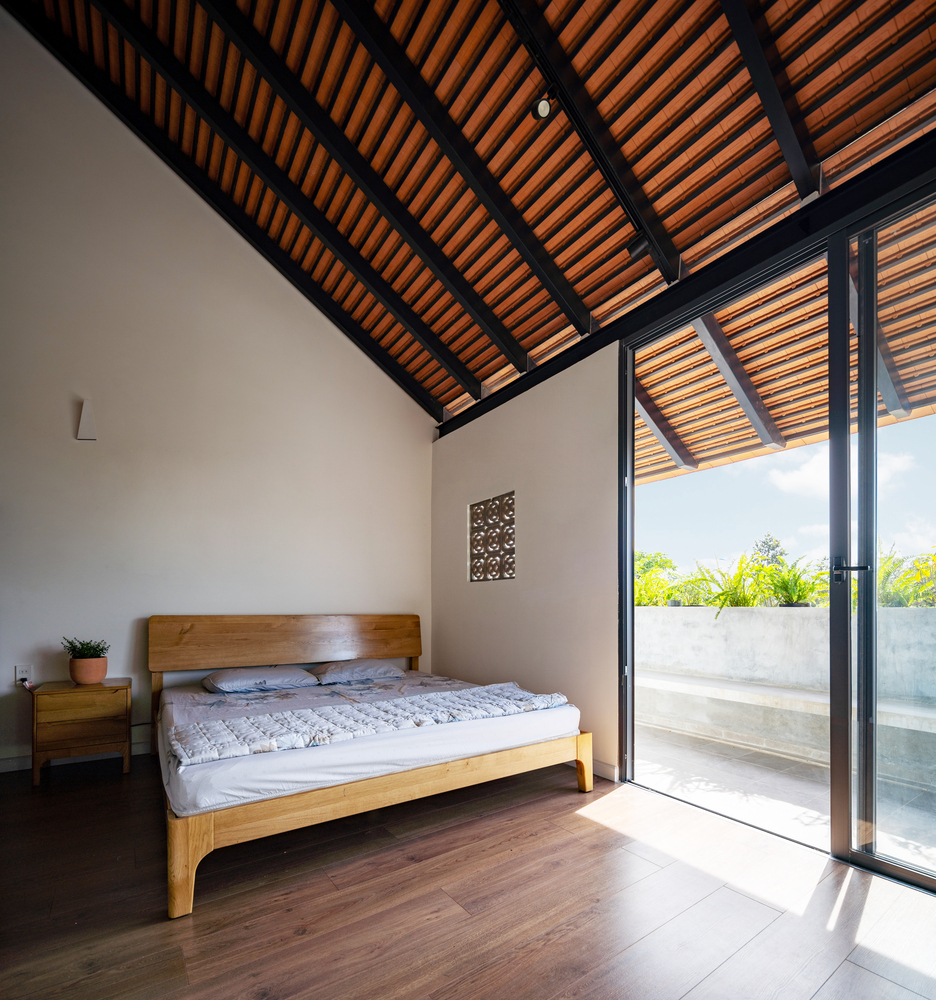 Phòng ngủ thiết kế tối giản với nội thất bằng gỗ sáng màu. Cũng tương tự như phòng khách, không gian phòng ngủ sở hữu cửa kính trượt trong suốt, giúp đón nhận toàn bộ nguồn sáng của thiên nhiên thoáng đãng.
