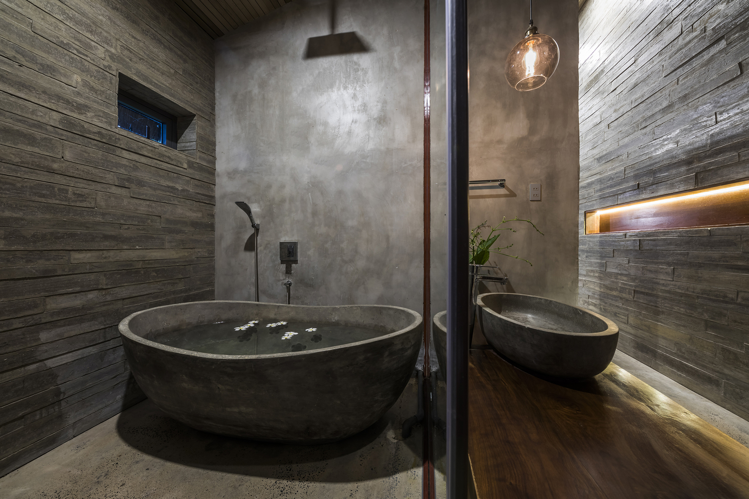 Phòng tắm được thiết kế như một ốc đảo riêng tư, vật liệu thô mộc với gam màu xám cùng hệ thống đèn vàng ấm áp.