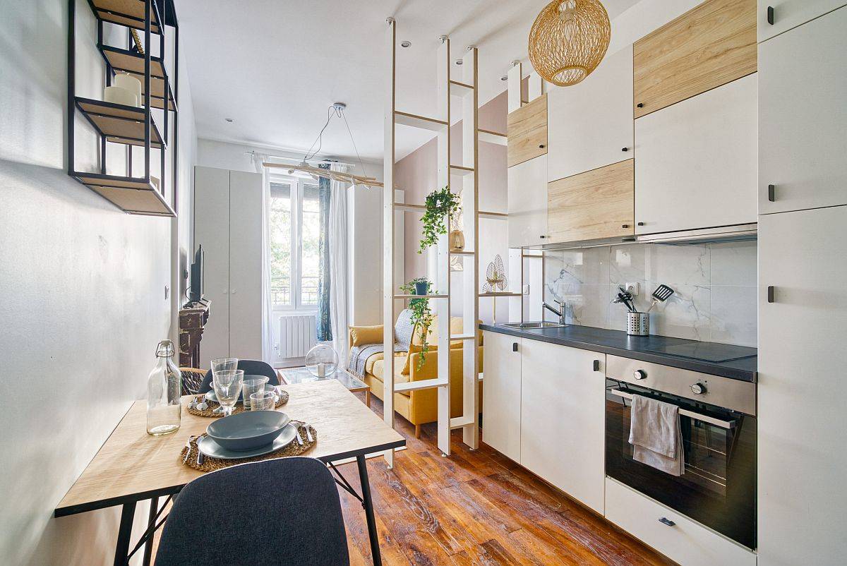 Một vách ngăn bằng gỗ sơn màu trắng với chiều cao kịch trần dùng để phân vùng phòng khách và phòng bếp một cách nhẹ nhàng thoáng sáng. 