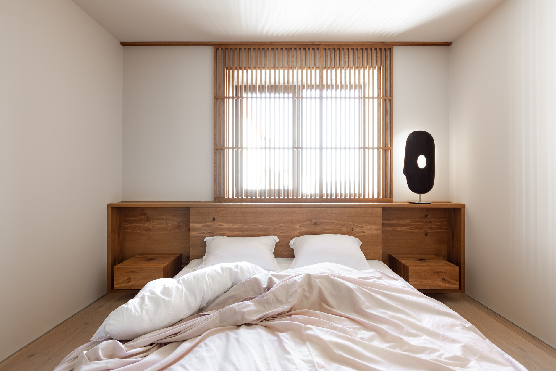Chiếc giường thấp sàn đa năng này được đặt gia công theo bản phác thảo của NTK nội thất Rina Lovko. Khu vực phía trên nối liền với táp đầu giường cân xứng, tạo nên vẻ đẹp hài hòa, cân đối cho phòng ngủ kiểu Nhật.