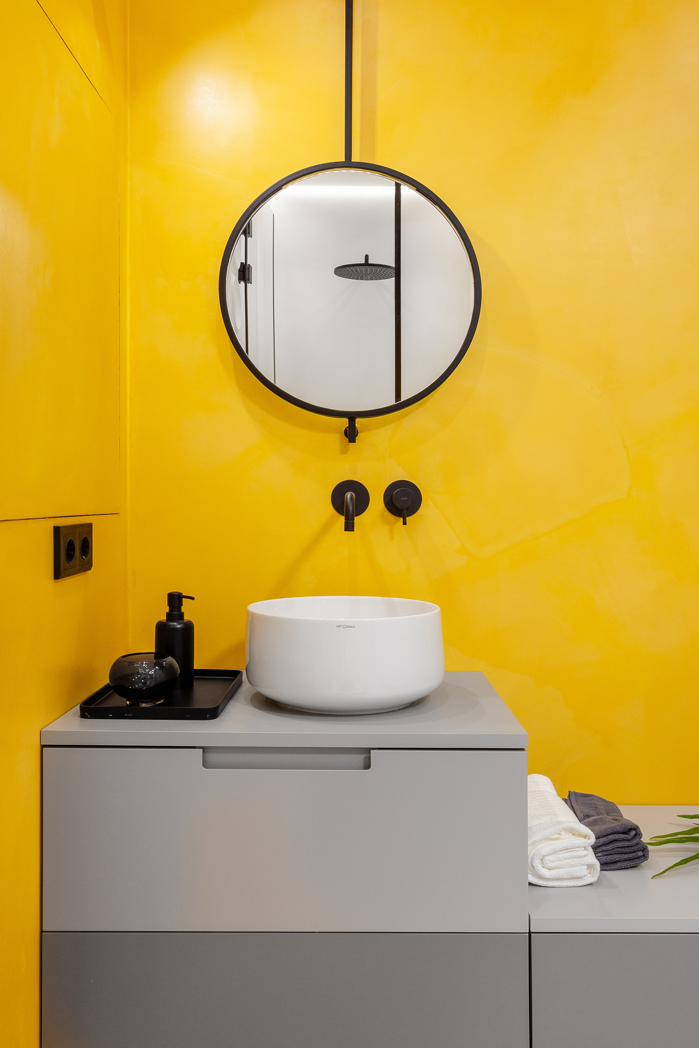 Nếu gam màu xám mang lại sự thanh lịch thì màu vàng lại rất trẻ trung. Ở phòng tắm này, tường phòng tắm sơn kín một sắc vàng, riêng tủ lưu trữ màu xám cùng vài chi tiết nhỏ màu đen tuyền khiến nó trở nên có tiết chế và sang trọng hơn.