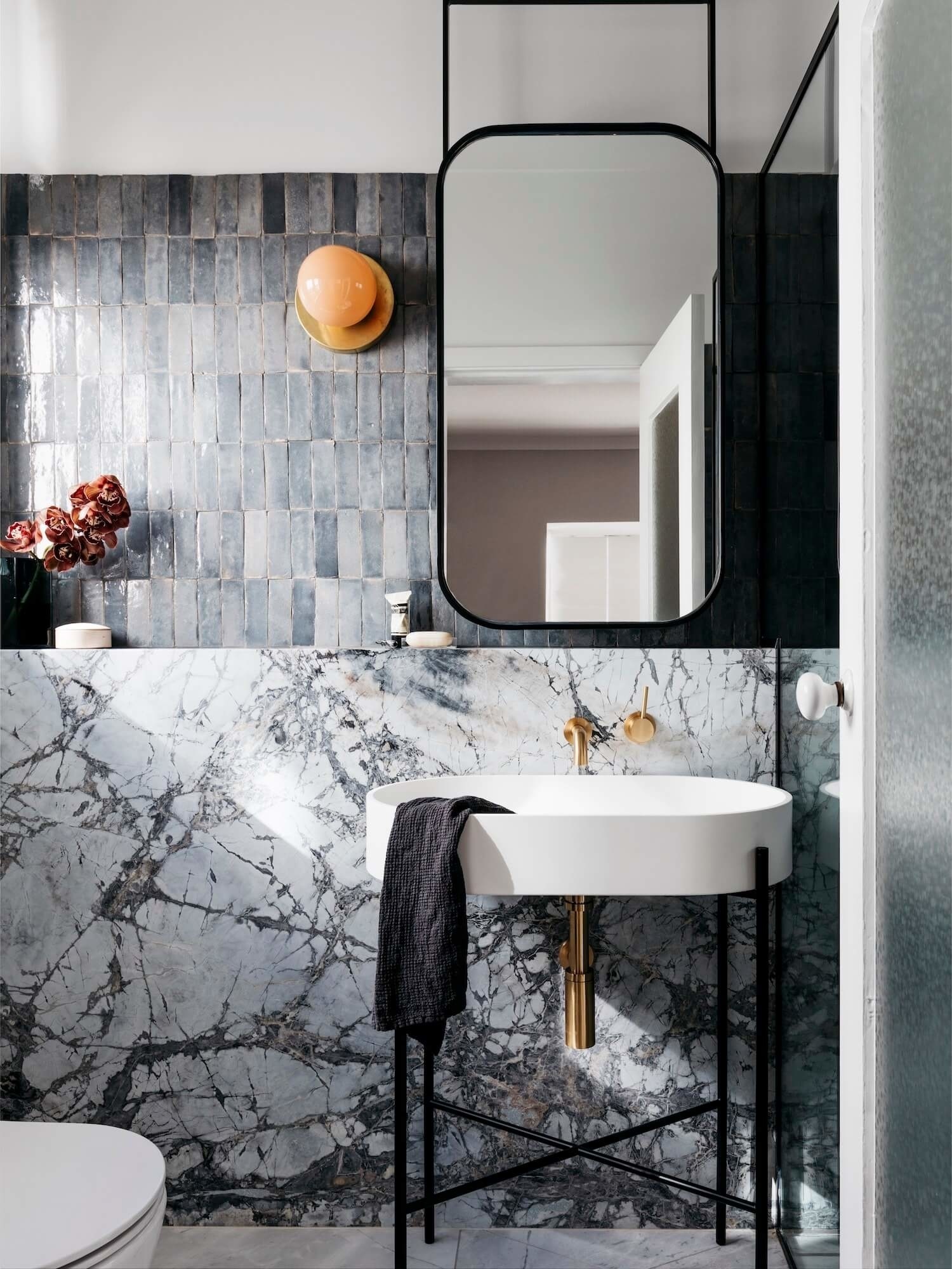 Dự án thiết kế nội thất của Decus Interiors, Sydney (Úc) mang lại sự lôi cuốn cho phòng tắm nhỏ nhờ kết hợp những viên gạch xám ốp dọc theo bức tường trên bồn rửa, phần tường bên dưới sử dụng đá cẩm thạch mang lại vẻ đẹp đa dạng, sắc sảo.