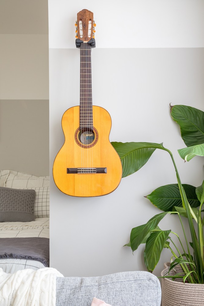 Bức tường bên ngoài phòng khách, góc chuyển tiếp vào phòng ngủ được trang trí bằng một cây đàn guitar của chủ nhân, giúp cho không gian thêm phần lãng mạn. Những chậu cây cảnh tươi xanh cũng góp phần mang không khí thiên nhiên vào bên trong căn hộ nhỏ.