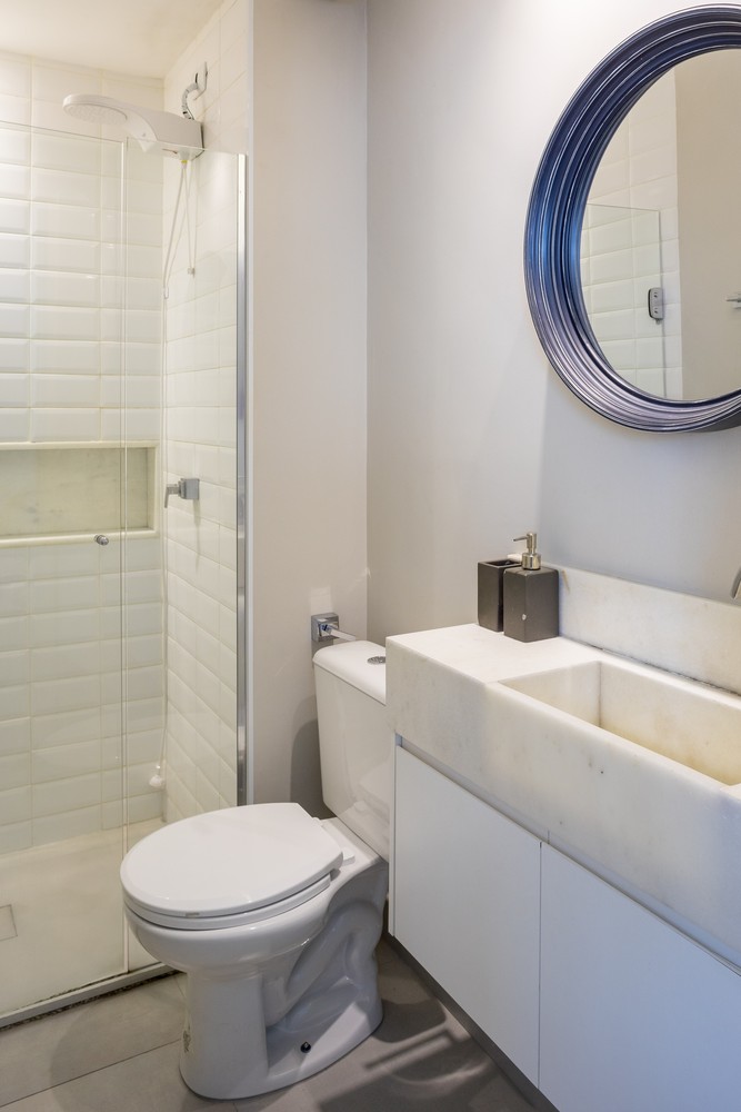 Phòng tắm và nhà vệ sinh thiết kế tích hợp với vách ngăn bằng kính trong suốt phân vùng hai khu vực. Bên trên bồn rửa là tấm gương tròn với viền khung bắt mắt, vừa để trang trí cho bức tường bớt đơn điệu, vừa phản chiếu ánh sáng và hình ảnh cho căn phòng như được 'nới rộng' hơn.