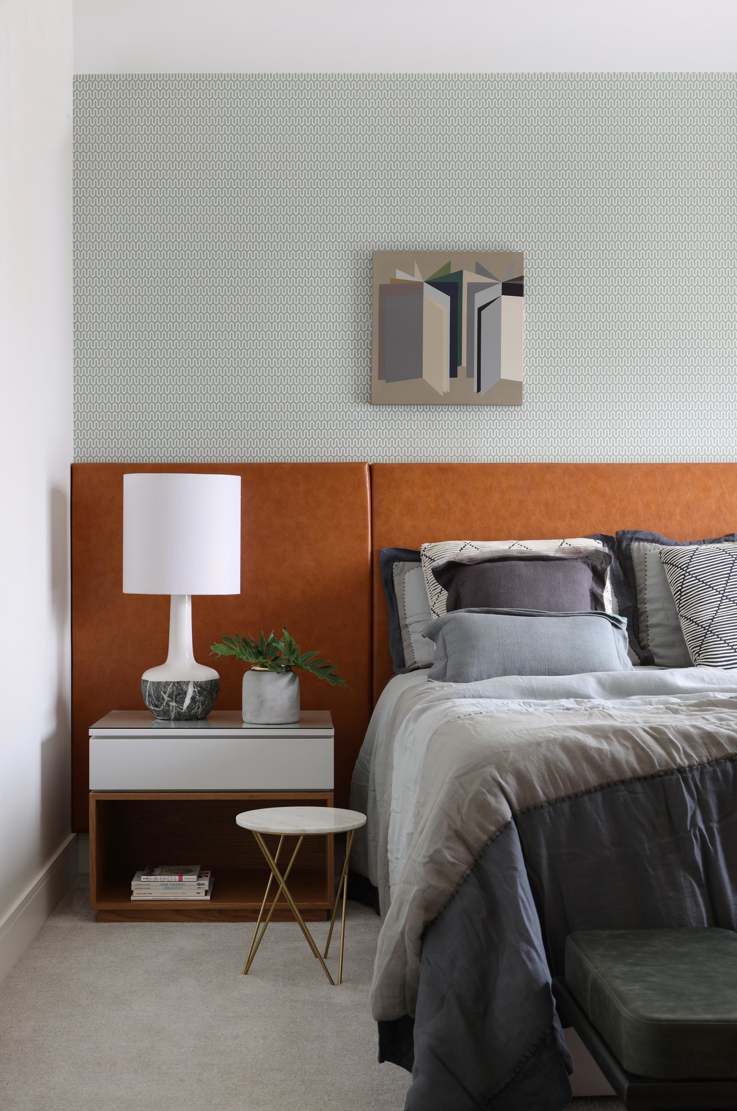 Nếu bức tường lựa chọn kiểu giấy dán màu xám họa tiết trang nhã, tạo điểm nhấn giữa phông nền sơn trắng thì riêng đầu giường lại nổi bật với gam màu cam gạch. Nó được thiết kế với kích thước kéo dài toàn bộ chiều rộng căn phòng, giúp cho giường và táp đầu giường đều có cùng 'điểm tựa'.