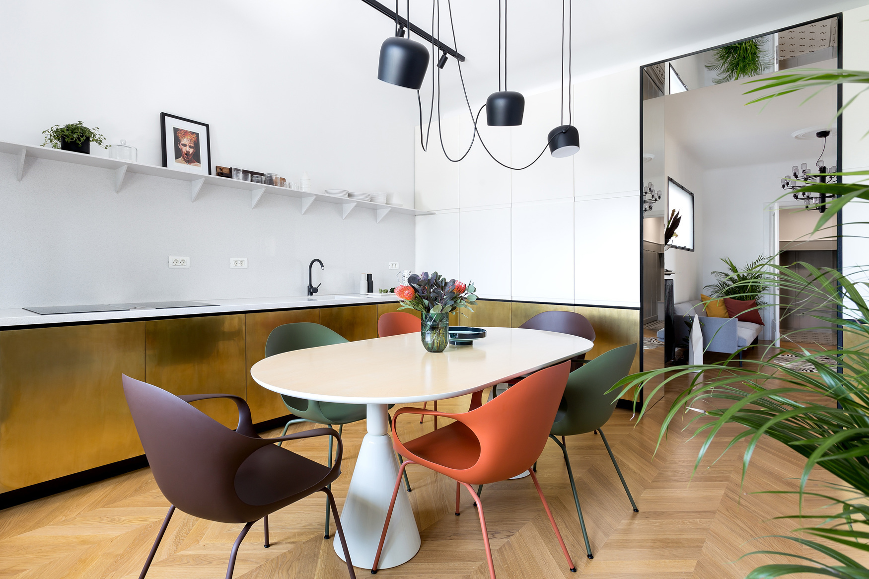 Phòng bếp kết hợp phòng ăn trong căn hộ tại Thủ đô Bucharest (Rumani) do Bogdan Chokodeik thiết kế với bộ ghế ăn nhiều màu sắc nổi bật xung quanh chiếc bàn hình oval. Ngoài ra nó còn gây ấn tượng bởi hệ tủ bếp dưới ốp đồng thau sang chảnh.