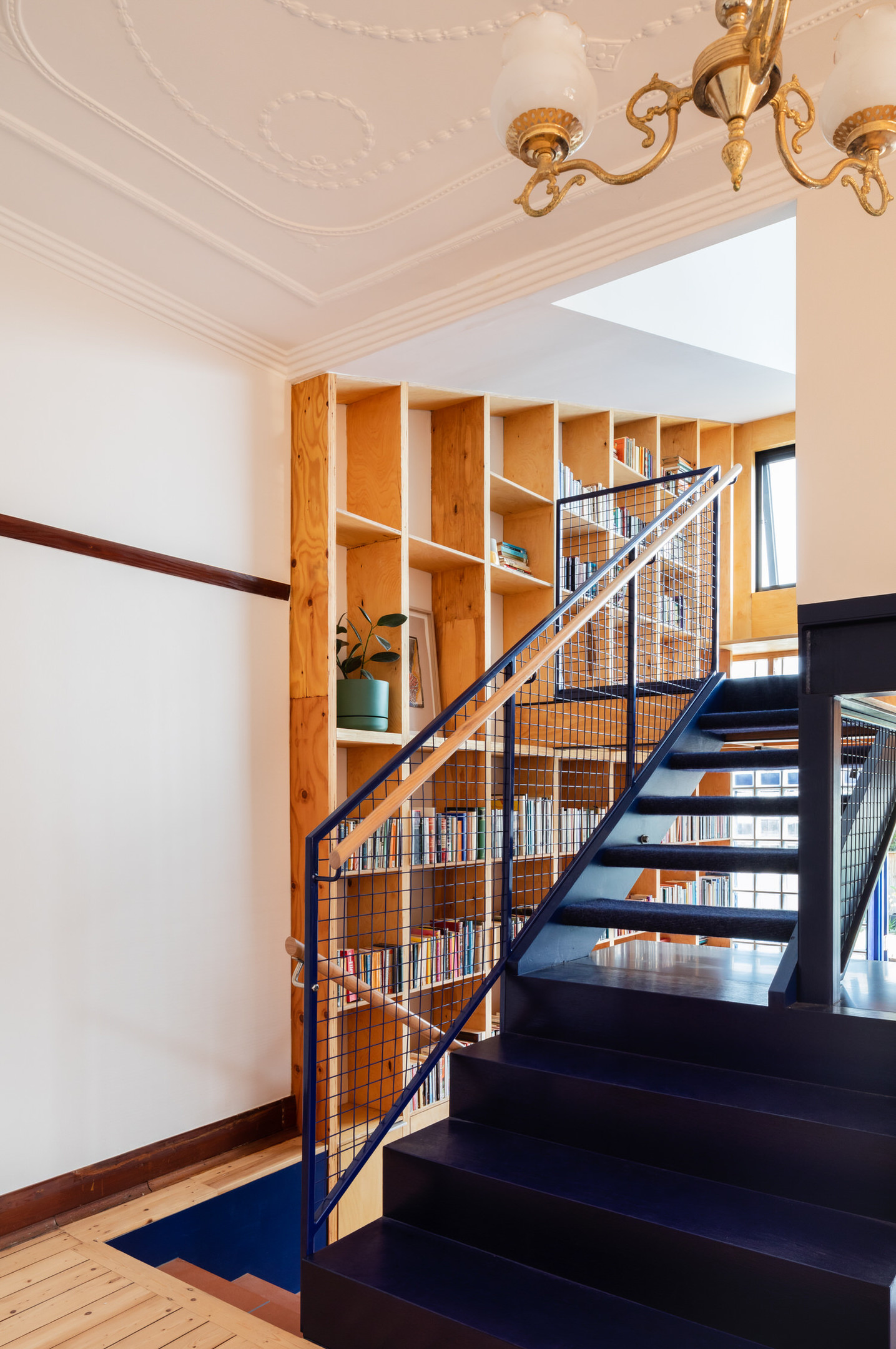 Tầng 1 và tầng 2 được chuyển tiếp bằng chiếc cầu thang màu xanh lam đậm vững chãi và nổi bật nhờ sắc màu tương phản với tổng thể. 