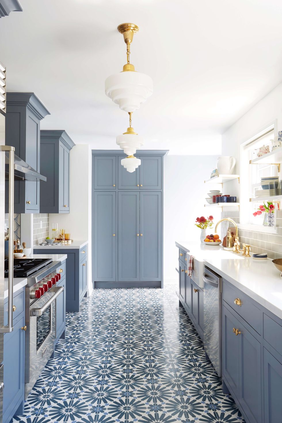 Không gian phòng bếp dài và hẹp trở nên tươi tắn nhờ gạch lát sàn có hoa văn màu xanh lam nổi bật. Khi kết hợp cùng tone màu xanh xám nhạt của hệ thống tủ lưu trữ càng thêm phần quyến rũ.