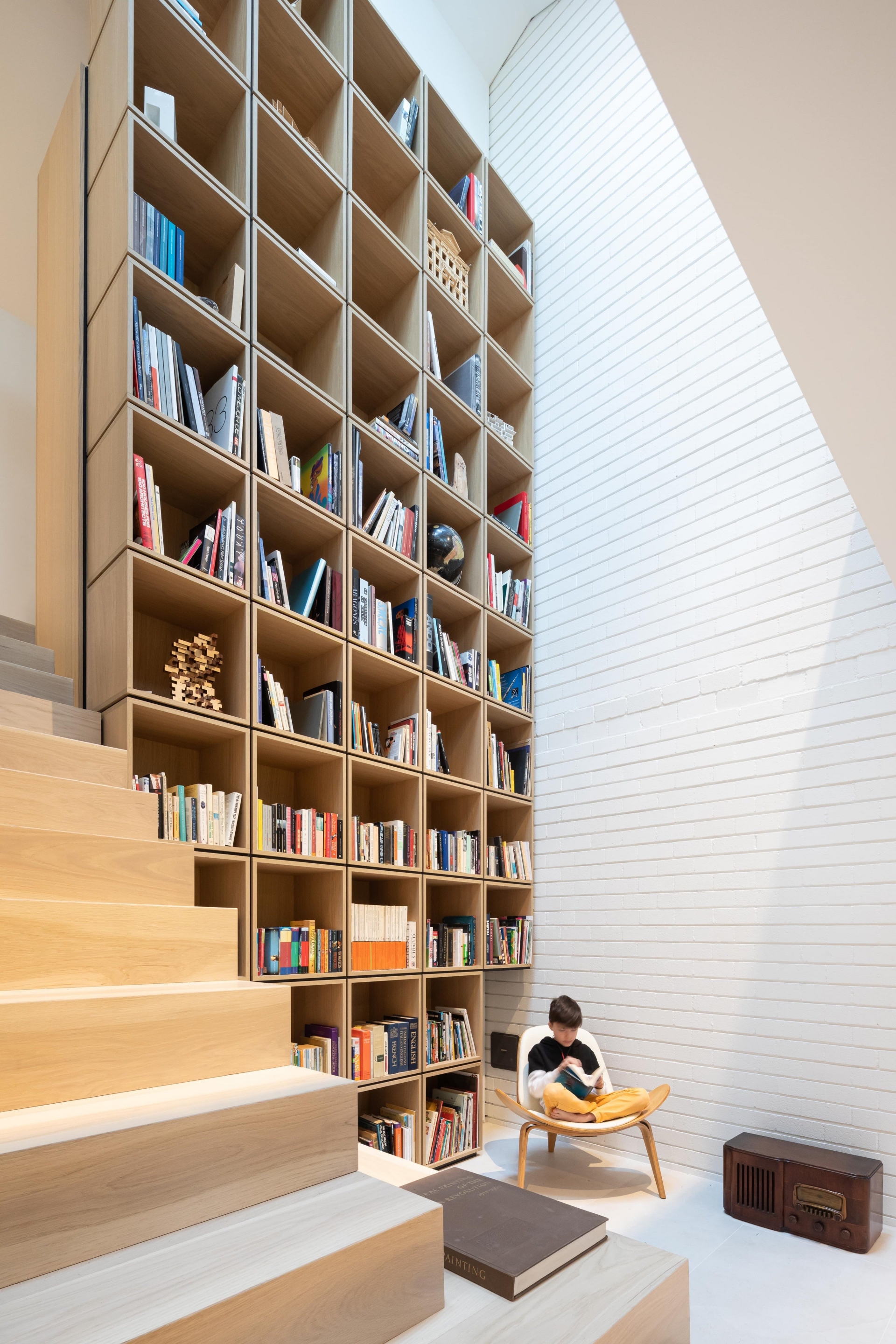 Thư viện mini trong ngôi nhà Vancouver (Canada) do RSAAW Studio thiết kế được hình thành bởi các hộp gỗ sáng màu xếp chồng lên nhau. Các tủ gỗ được đóng vào sát cầu thang tạo thành bức tường nối cả tầng 1 và tầng 2 của ngôi nhà.