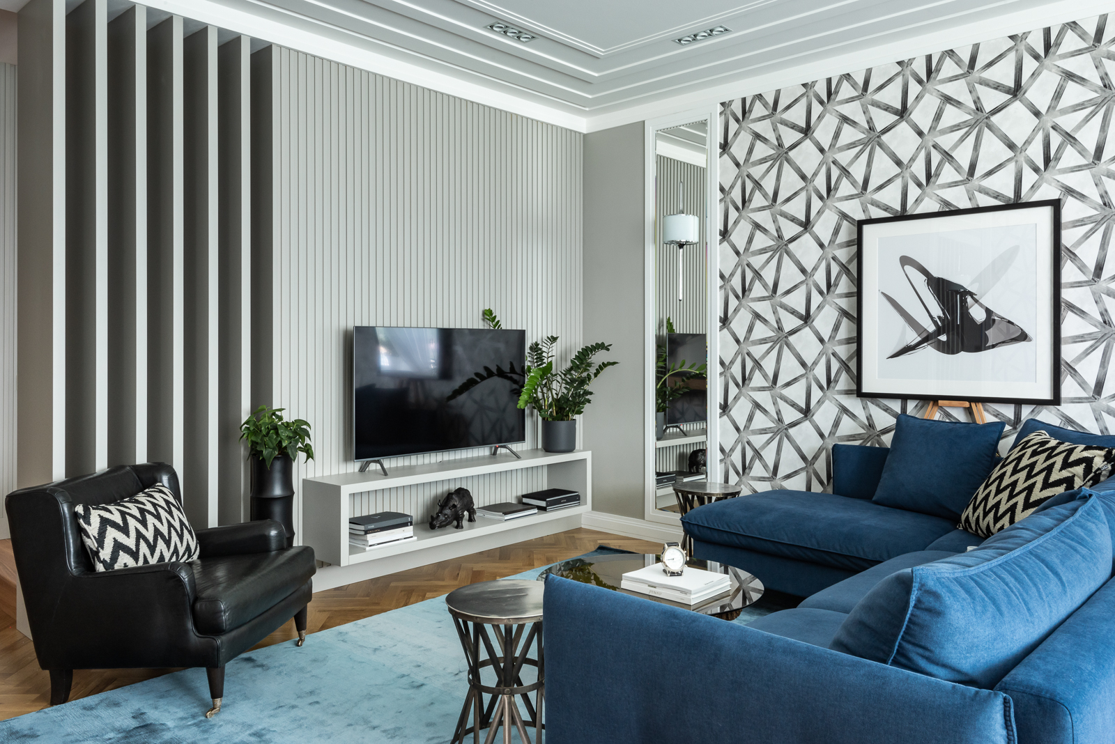 NTK nội thất Ksenia Yerlakova đã khéo léo kết hợp ghế sofa với chất liệu vải nhung màu xanh coban bắt mắt với chất liệu da thuộc màu đen của chiếc ghế bành tạo cái nhìn mạnh mẽ, vững chãi cho phòng khách trong căn hộ ở Yekaterinburg (Nga).