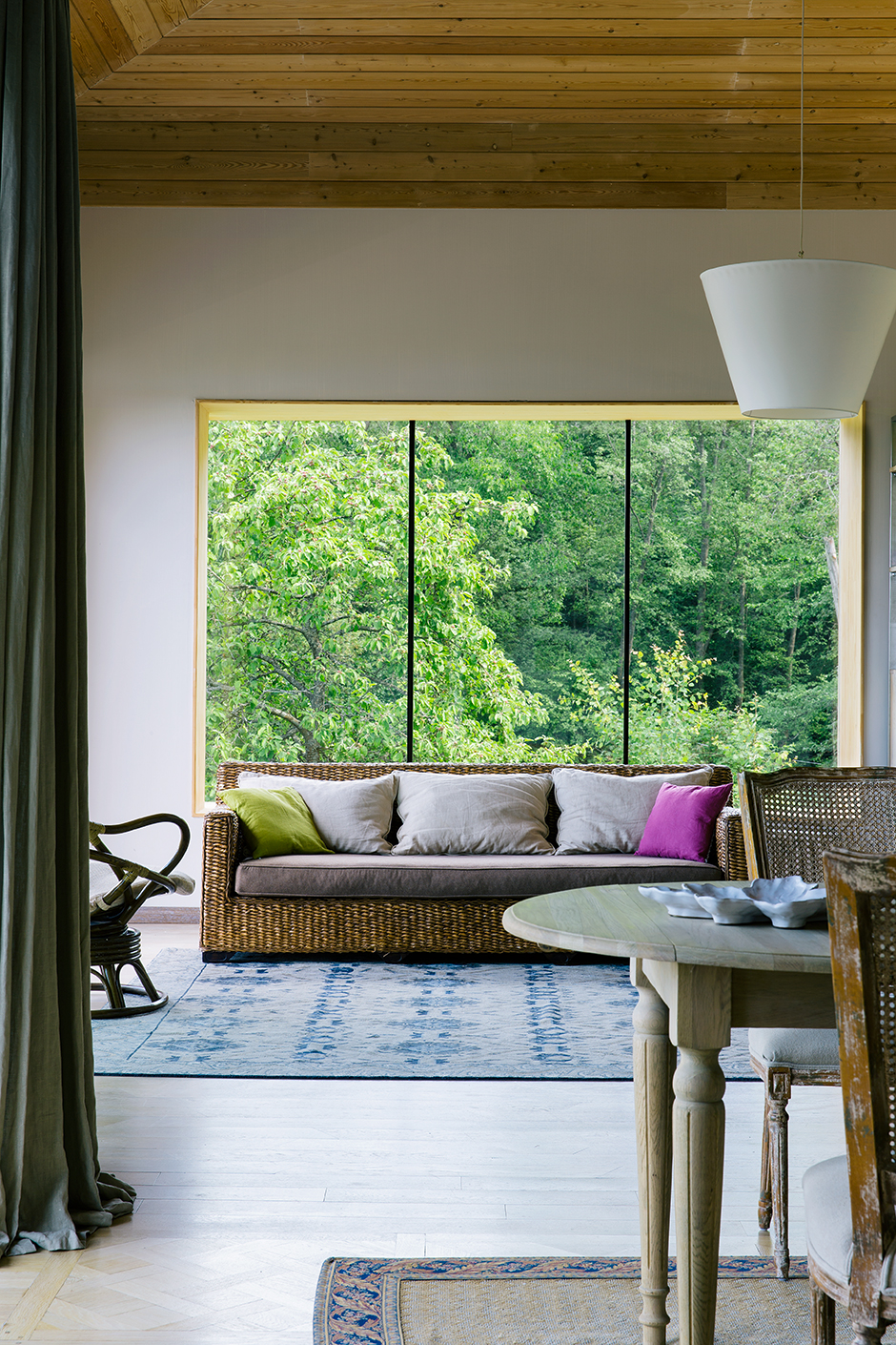 Ngôi nhà của NTK nội thất Ilya Sologubovsky với khung cảnh cây cối tươi xanh bên ngoài ô cửa sổ lãng mạn, thêm vào chiếc ghế sofa và ghế bập bênh chất liệu mây tre đan khiến không gian càng thêm gần gũi với thế giới tự nhiên. 