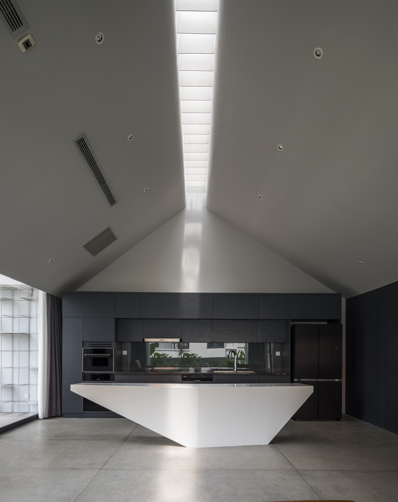 Giếng trời vừa thông gió vừa lấy sáng cho toàn bộ không gian sinh hoạt chung. Phòng bếp sang trọng với thiết kế kiểu chữ I, tủ bếp màu đen kết hợp đảo bếp trắng tạo nên sự tương phản ấn tượng.