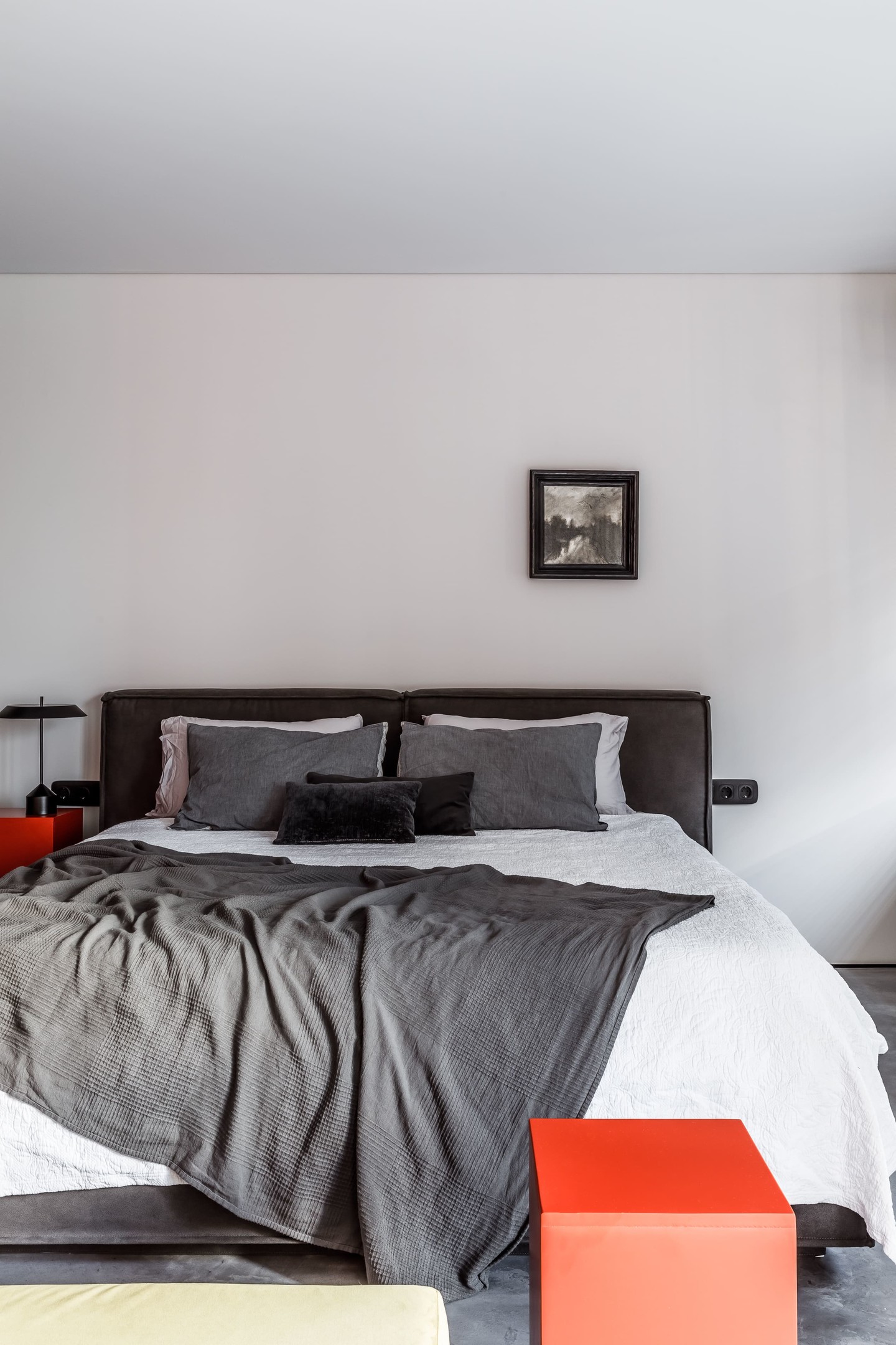 Phòng ngủ thiết kế tối giản từ màu sắc đến nội thất nhằm tạo sự thư giãn thoải mái, ít bị chi phối bởi nội thất cồng kềnh. Tone màu cơ bản vẫn sử dụng là trắng, xám, và sắc cam sáng bừng của ghế ngồi và táp đầu giường.