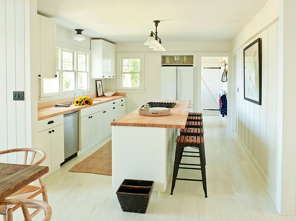 Phòng bếp thiết kế kiểu chữ I cùng đảo bếp tích hợp khu vực ăn uống chỉ sử dụng các sắc thái của gam màu trắng cho sàn nhà, tường và trần nhưng không đơn điệu nhờ mặt bàn và ghế ốp gỗ ấm áp.