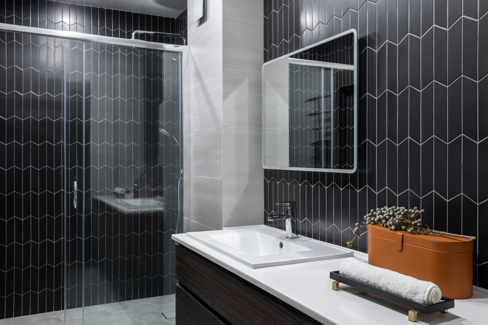 Phòng tắm là không gian duy nhất trong căn hộ không sử dụng gam màu xanh lam để trang trí, thay vào đó là gạch lát sàn và ốp tường tone màu trắng - đen sang trọng. Cửa kính trượt trong suốt giúp không gian này thông thoáng và đón sáng tốt hơn.