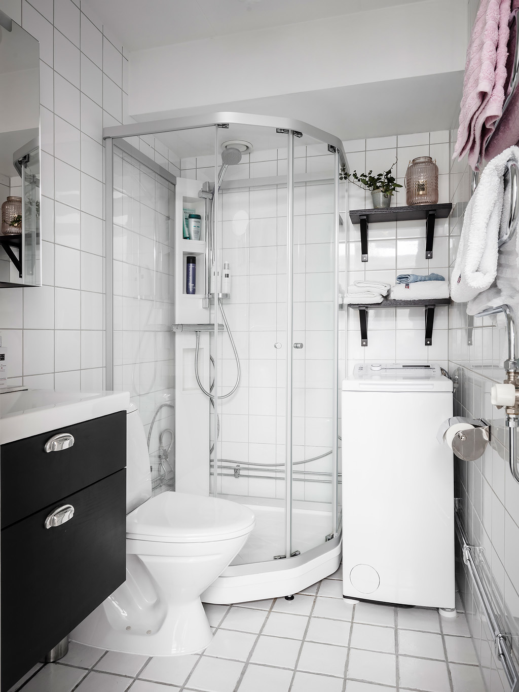 Phòng tắm và nhà vệ sinh tuy nhỏ nhưng đầy đủ tiện nghi, từ tủ vanity cho đến máy giặt, kệ mở và buồng tắm đứng phân vùng bằng cửa trượt trong suốt.