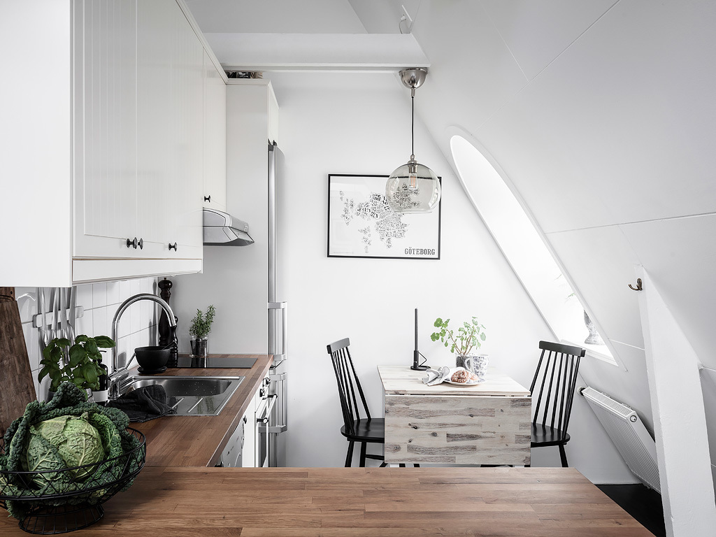 Phòng bếp và khu vực ăn uống được bố trí ở góc phải của phòng khách, thiết kế kiểu chữ L với mặt bàn gỗ như 'khoanh vùng' không gian nấu nướng và ăn uống. 