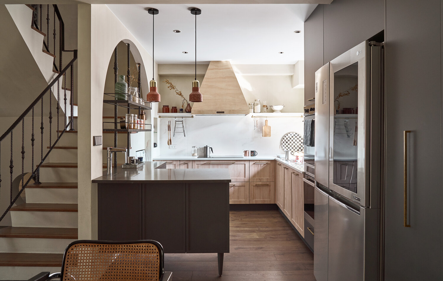 Phòng bếp được bố trí nhỏ gọn với khung cửa mái vòm cong cong tuyệt đẹp, kết hợp với kệ lưu trữ gọn gàng. Tone màu gỗ và trắng kết hợp cùng nhau cho khu vực nấu nướng vẻ đẹp tươi tắn.
