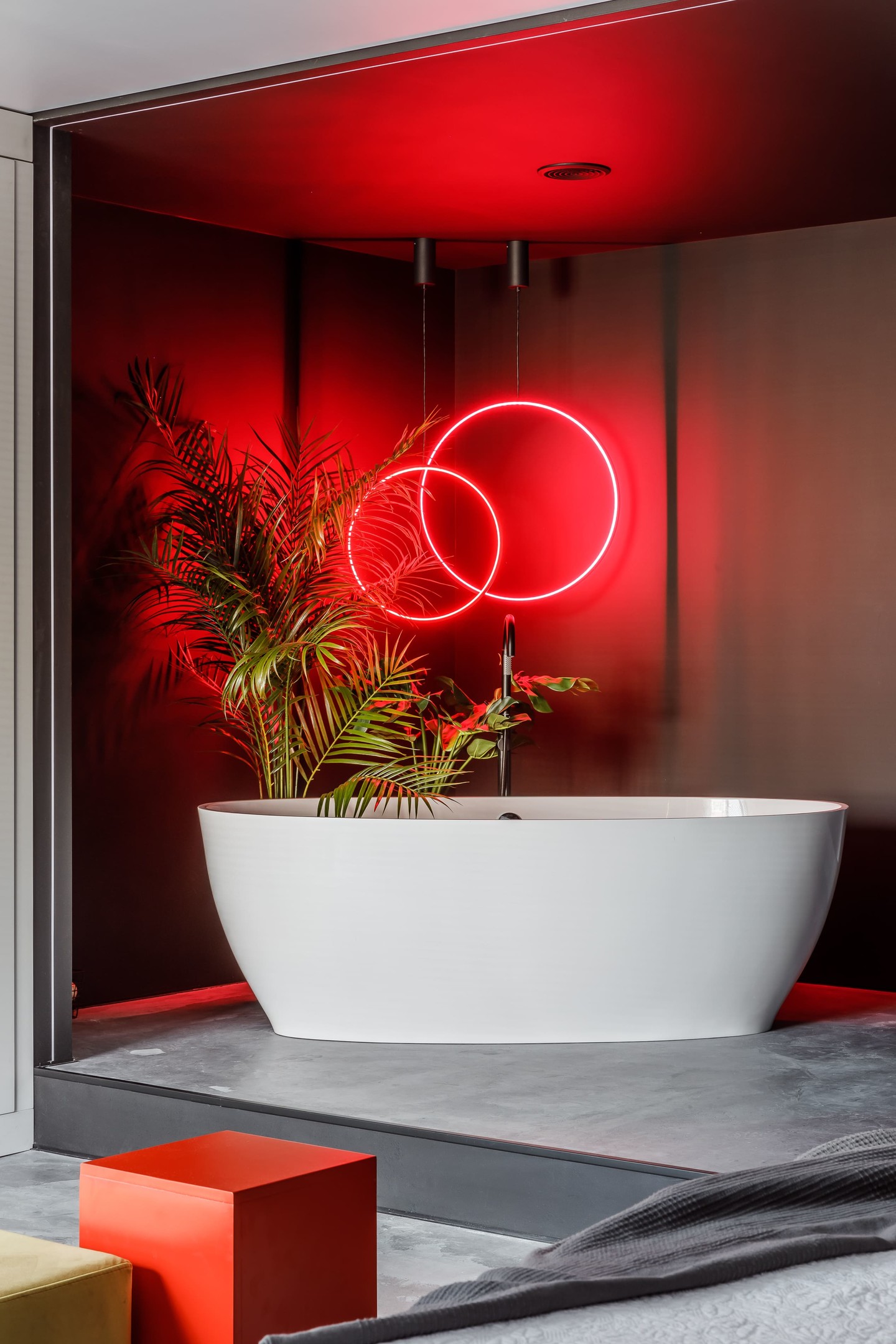 Phòng tắm thiết kế mở ấn tượng với bồn tắm nằm sứ trắng sáng bóng, kết hợp chậu cây cảnh cùng bộ đèn LED thả trần hình tròn lung linh, rực đỏ một góc phòng.
