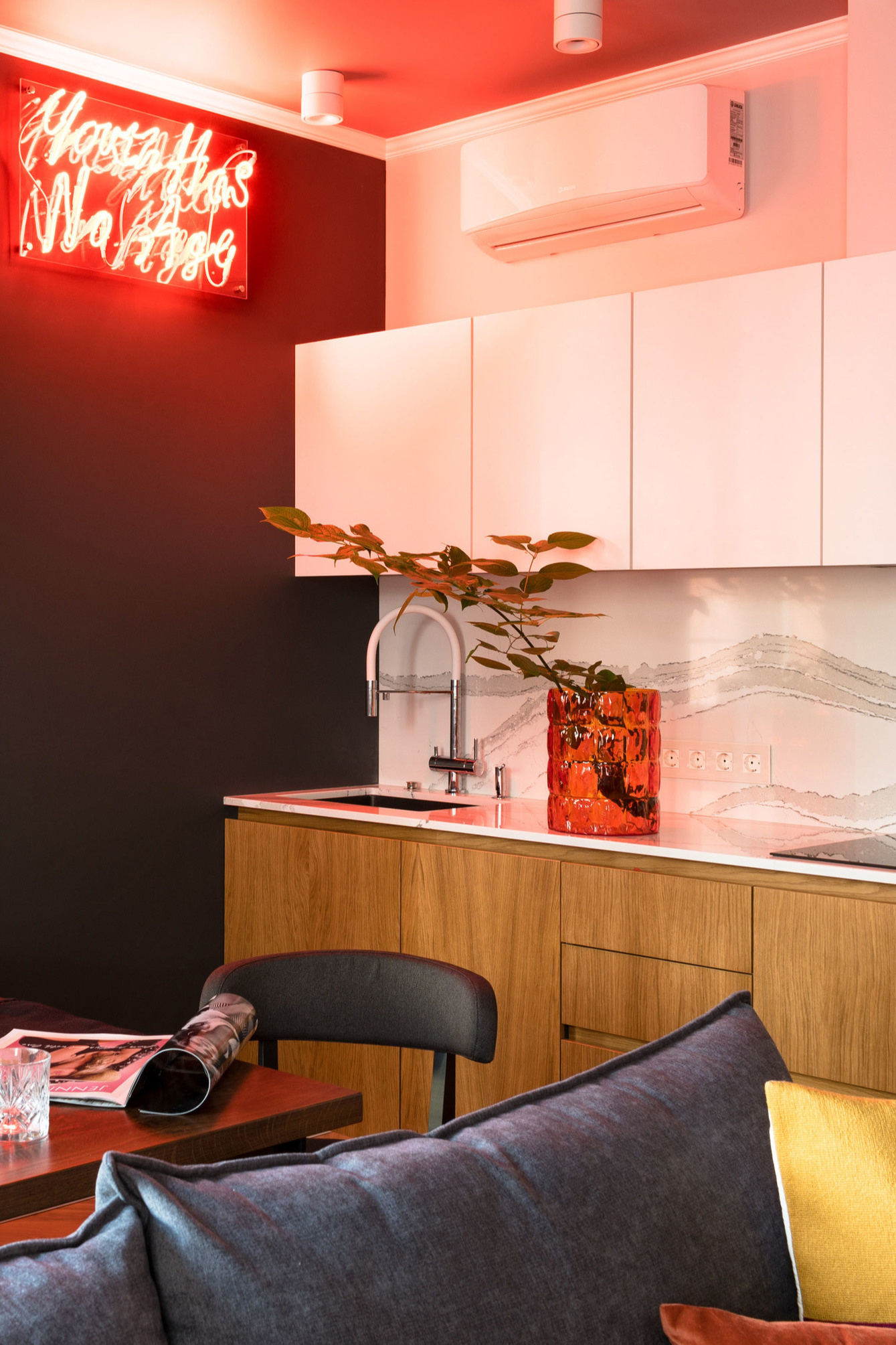 Phòng bếp có thiết kế kiểu chữ I, tủ bếp là sự kết hợp của sắc trắng và vật liệu gỗ nhẹ nhàng nhưng vẫn nổi bật nhờ bức tường sơn màu đỏ cùng đèn LED bắt mắt.