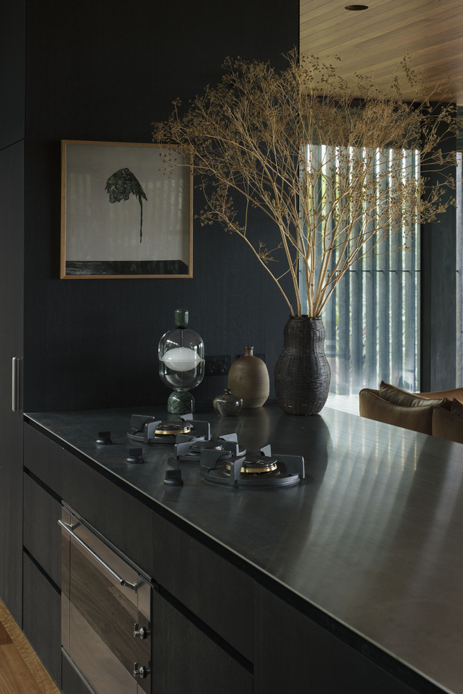 Phòng bếp thiết kế tối giản với bếp đôi cùng tone màu đen cho cảm giác sạch sẽ, sang trọng.  Những lọ hoa trang trí cũng giúp không gian nấu nướng thi vị hơn.