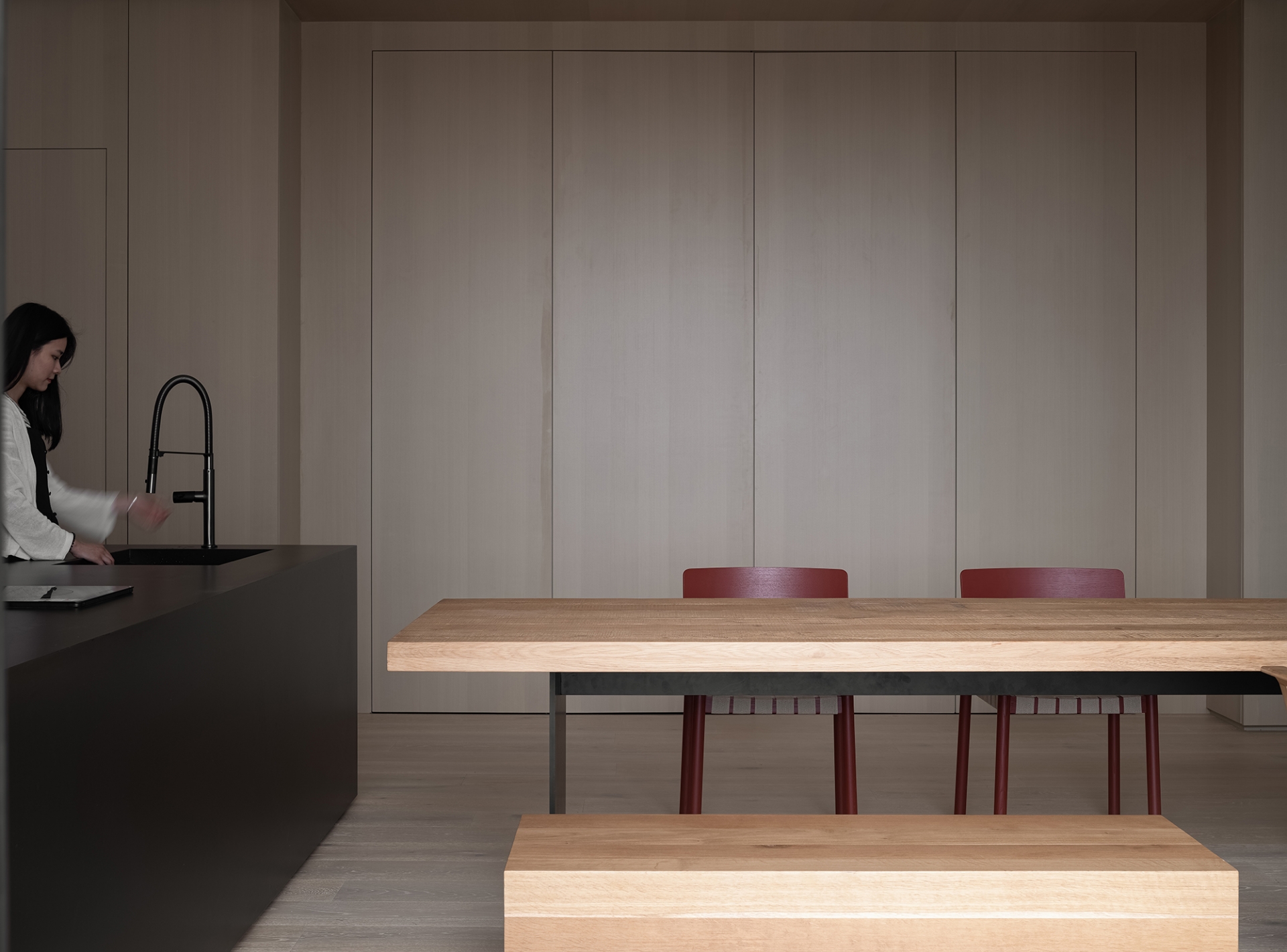 Khu vực phòng bếp với tone màu đen sang trọng, nội thất với đường nét tinh giản, tạo sự tương phản về màu sắc với hệ thống tủ lưu trữ cao kịch trần cũng như bàn ăn.