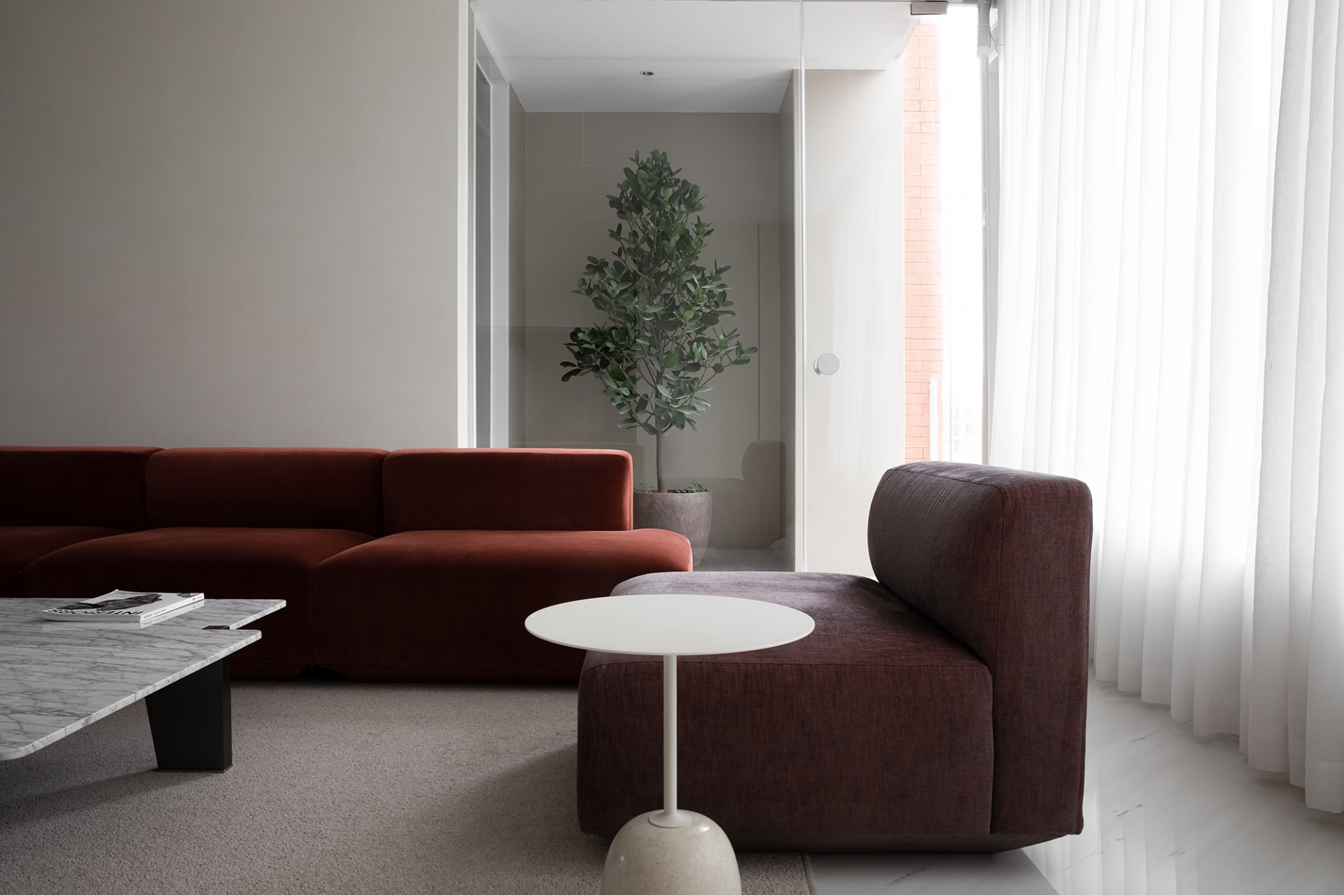 Phòng khách sử dụng ghế sofa màu đỏ không tay vịn cho cảm giác thanh thoát. Ghế bành sử dụng tone màu trầm ấm hơn, với chiếc bàn phụ màu trắng nhỏ xinh bên cạnh.