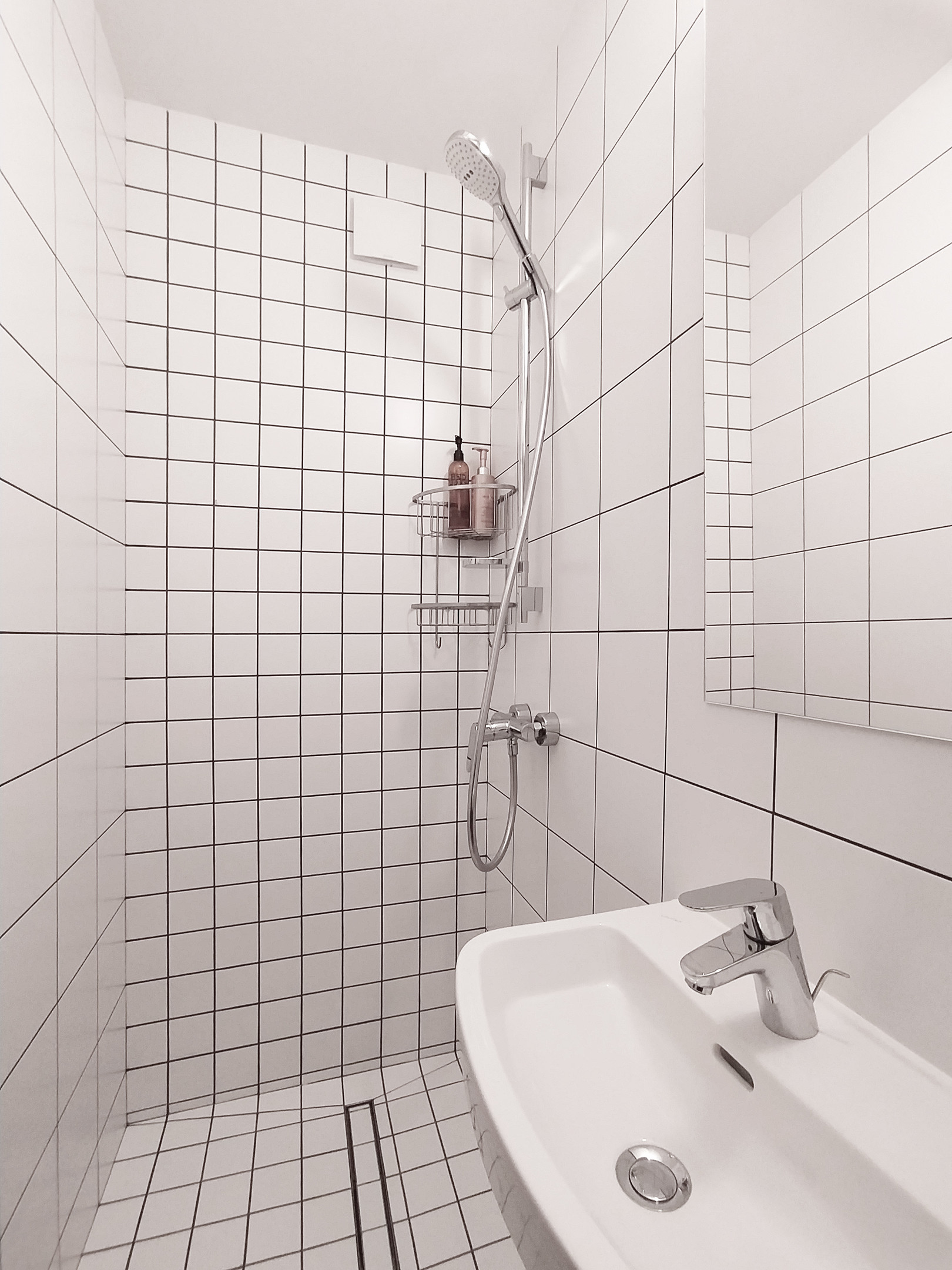 Buồng tắm với những viên gạch vuông kích thước to nhỏ tạo cảm giác sạch sẽ, phân vùng với gạch bông ở toilet. Tủ lưu trữ mặt gương soi giúp phản chiếu hình ảnh và ánh sáng cho phòng tắm nhỏ rộng rãi hơn.