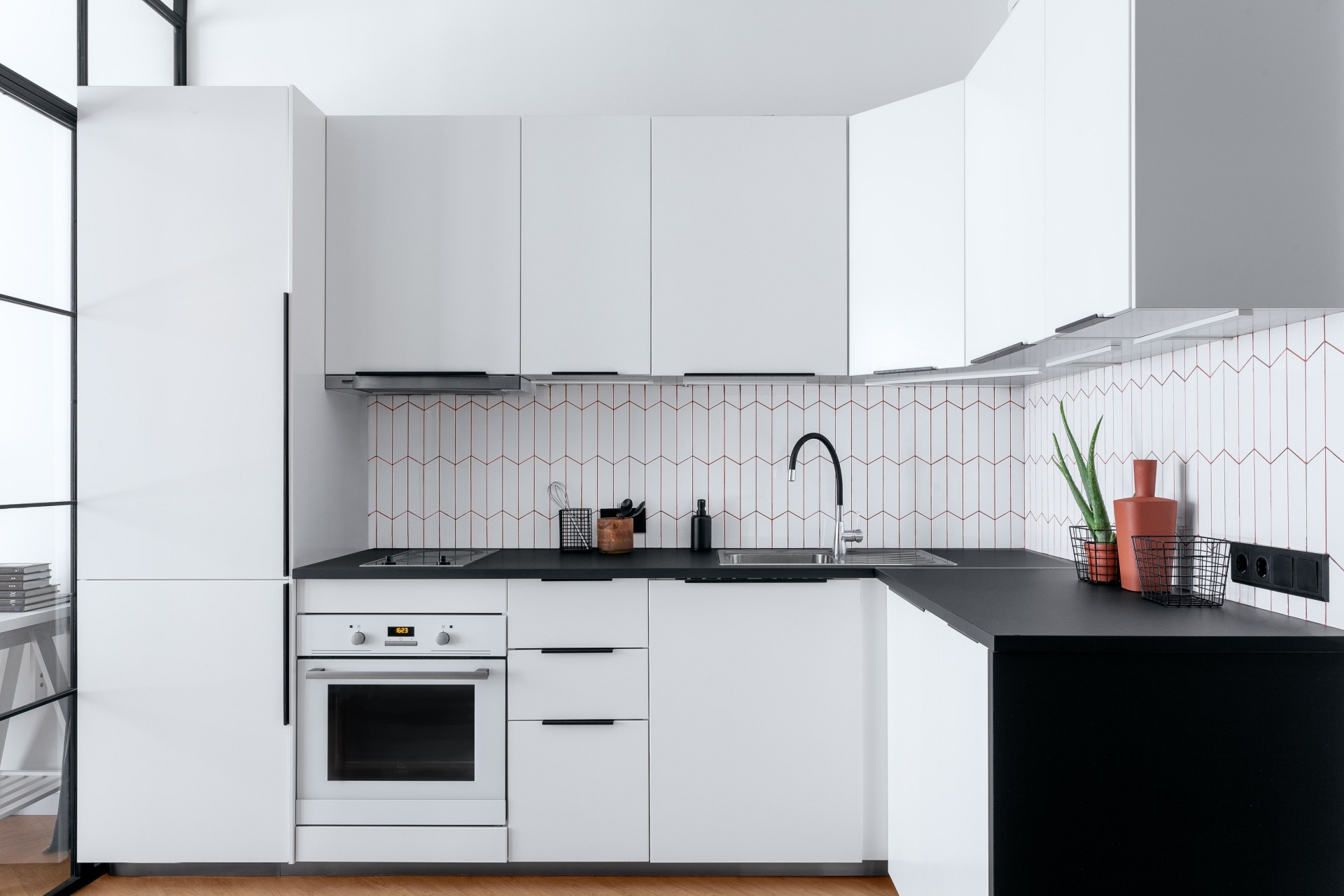 Khu vực phòng bếp lựa chọn thiết kế tủ chữ L, phù hợp với cấu trúc của căn hộ, đồng thời rất sang trọng nhờ sự kết hợp mặt bàn đá đen và tủ trắng cổ điển.