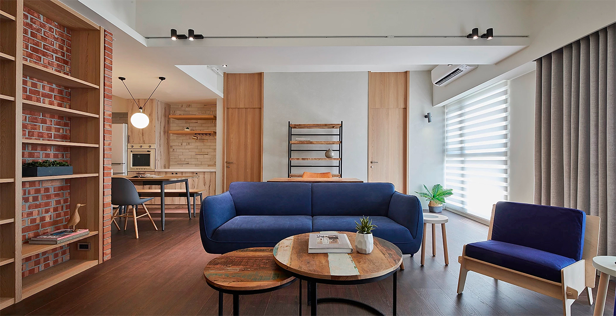 Căn hộ sử dụng tone màu trắng và nâu tự nhiên của gỗ làm chủ đạo. Khu vực phòng khách bố trí ghế sofa và một chiếc ghế lắp ráp với màu xanh coban nổi bật.