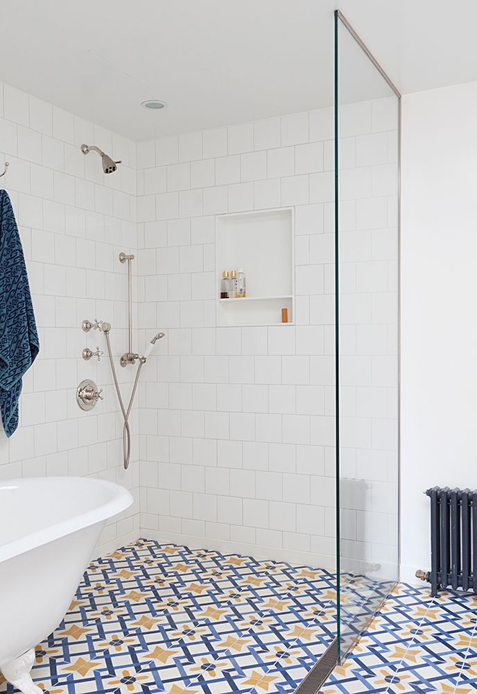 Trong không gian phủ đầy sắc trắng của gạch ốp tường hình vuông, màu sơn tường và chiếc bồn tắm trắng sứ thì những viên gạch họa tiết xanh lam - vàng đã trở thành điểm nhấn cho không gian thêm nổi bật.