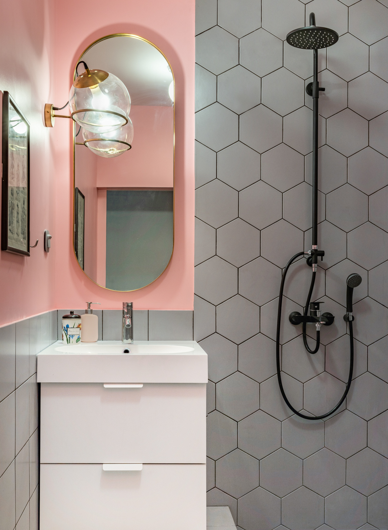 Phòng tắm siêu nhỏ nhưng vẫn nổi bật nhờ gạch ốp tường họa tiết tổ ong kết hợp với một mảng tường sơn màu hồng phấn, tấm gương oval phản chiếu ánh sáng từ đèn gắn tường quả cầu lấp lánh.