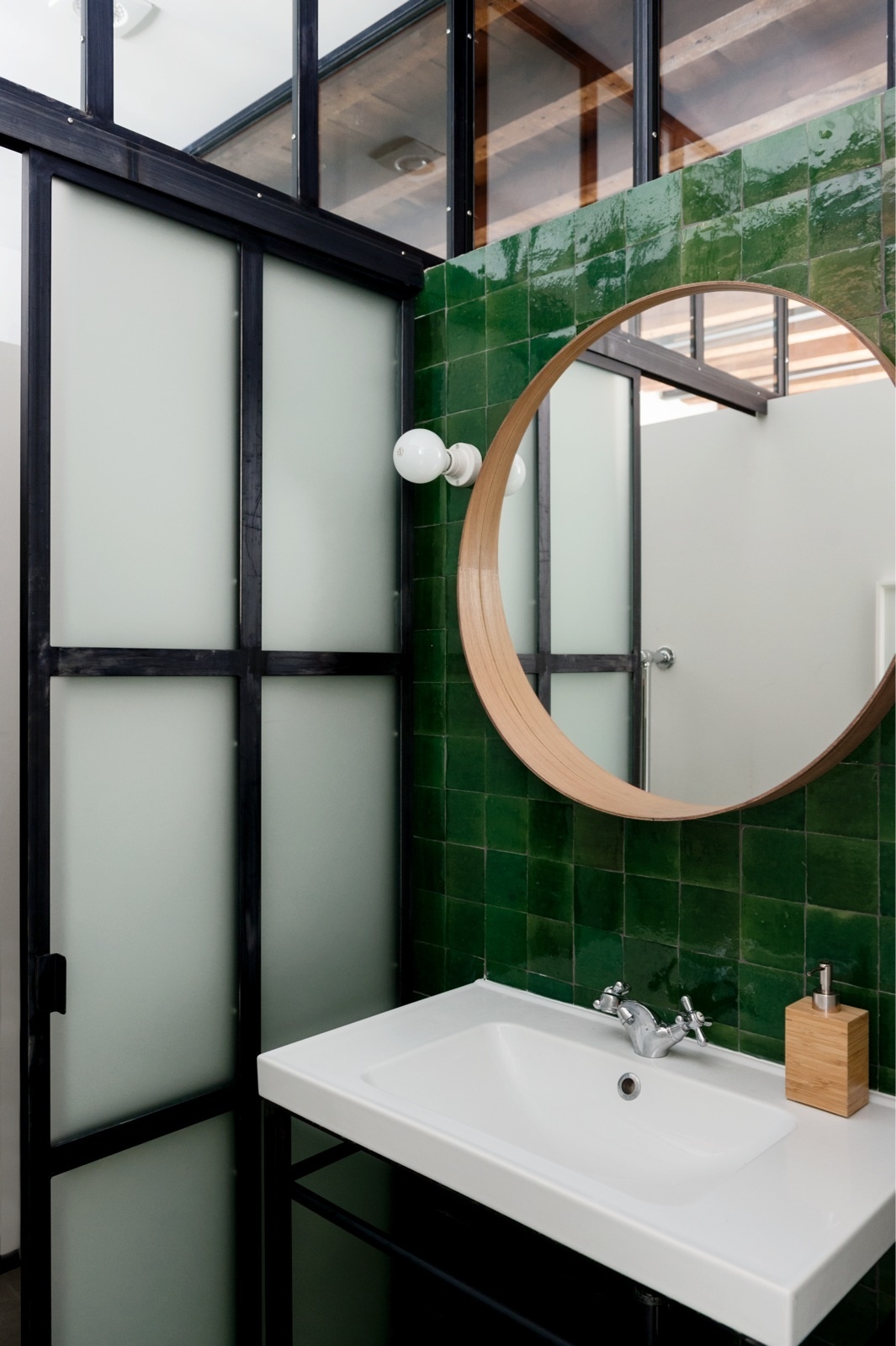 Tại khu vực bồn rửa, NTK đã lắp đặt tấm gương tròn giúp đánh lừa thị giác, cho phòng tắm siêu nhỏ trở nên rộng hơn so với diện tích thật. Cùng với đó là những viên gạch vuông màu xanh ngọc lục bảo bề mặt bóng loáng thu hút không kém.