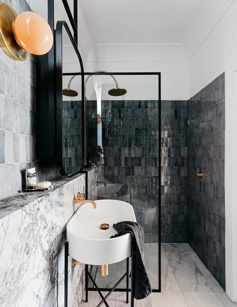 Nếu bạn yêu thích phong cách tối giản nhưng vẫn sang trọng thì thiết kế phòng tắm kết hợp gạch thẻ ốp dọc tường buồng tắm và đá cẩm thạch tự nhiên ở khu vực bồn rửa sẽ đáp ứng gu thẩm mỹ của bạn.