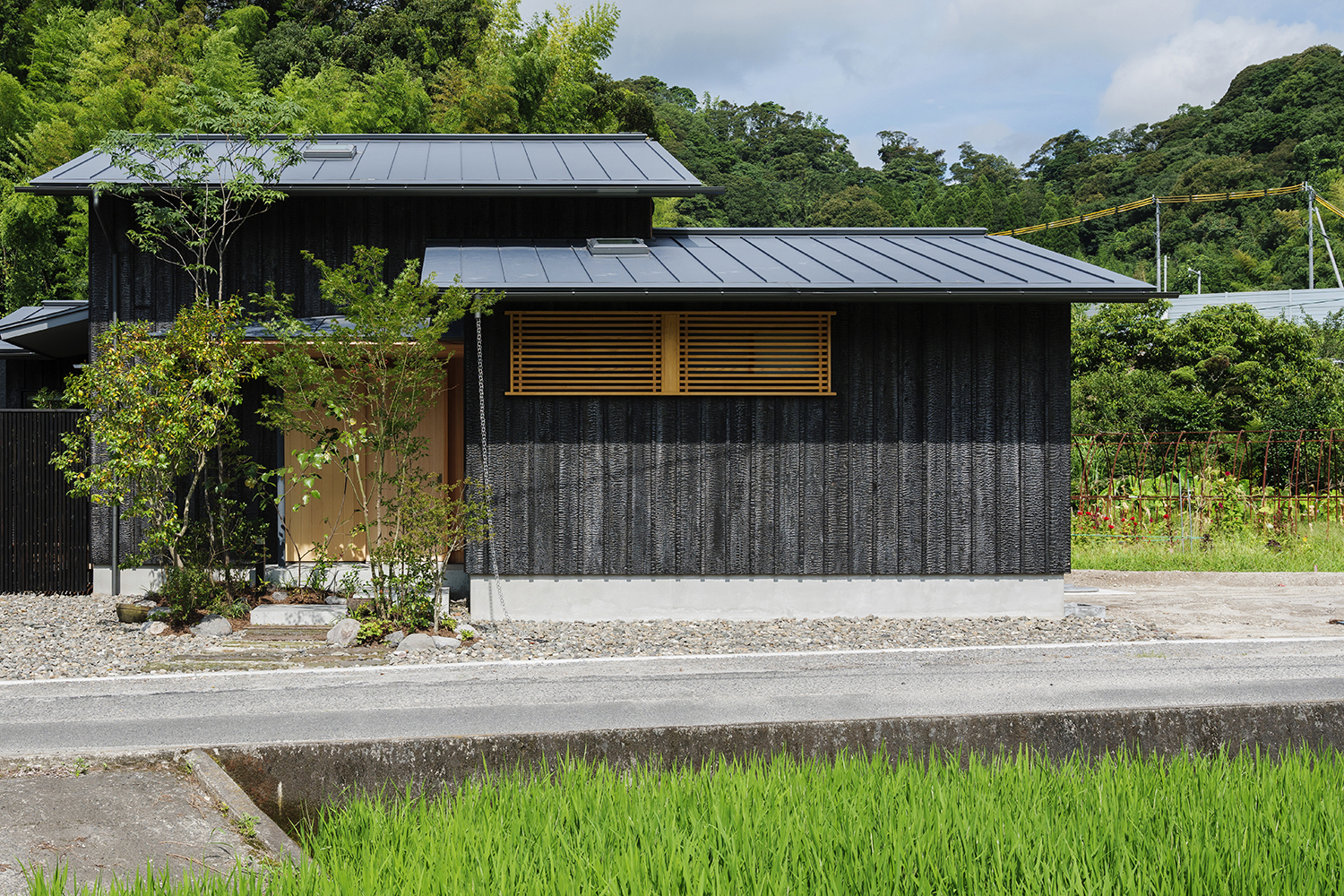 Ngôi nhà gỗ với mặt tiền màu đen tuyền giữa khung cảnh cánh đồng lúa ngát xanh tạo nên vẻ đẹp vừa nên thơ vừa vững chãi. 