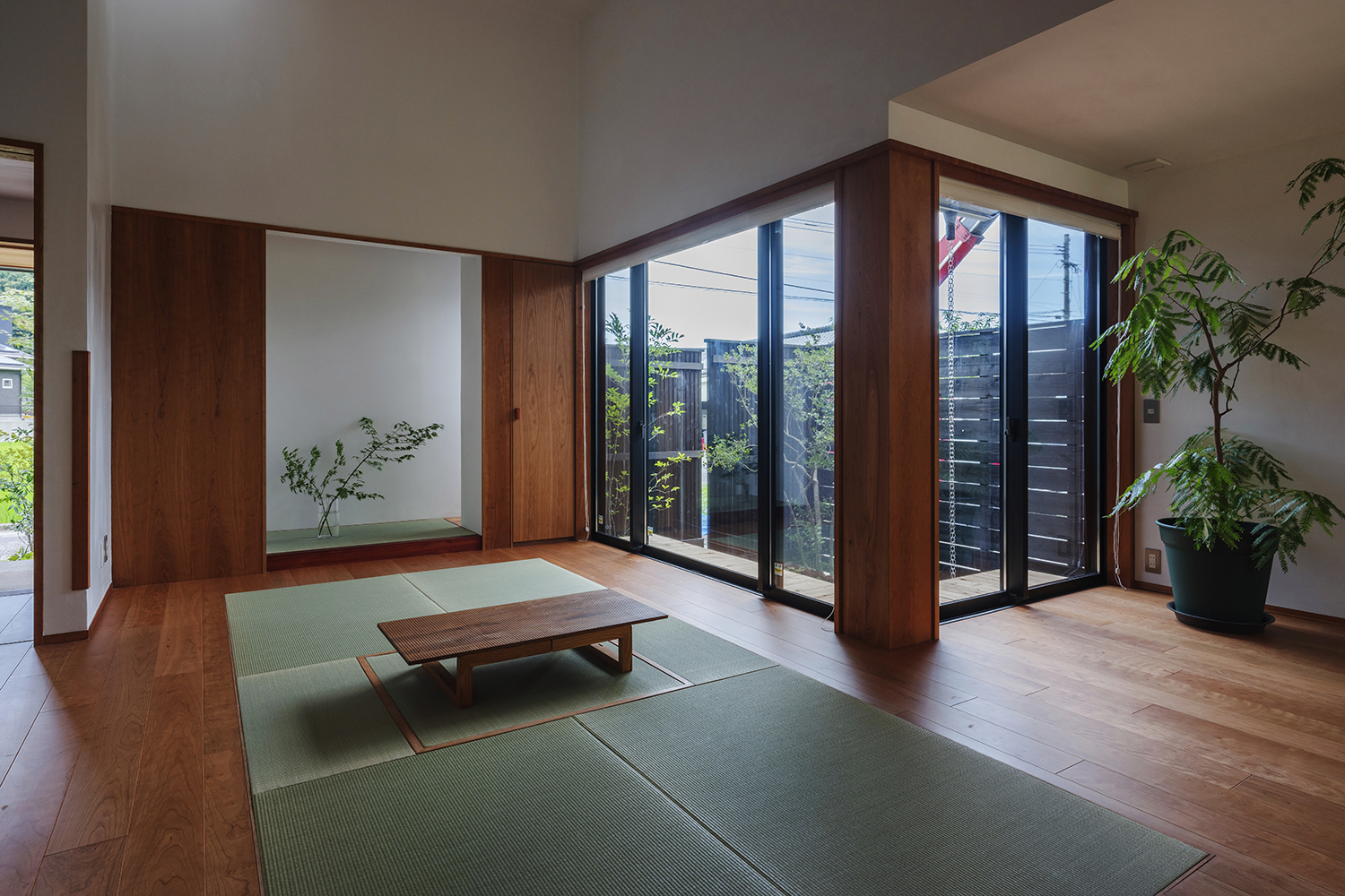 Dưới 3 tầng mái, KTS có chủ ý thay đổi chiều cao trần. Phần trần cao là phòng khách thiết kế mở, những bức tường kính xung quanh kết hợp cây cảnh tạo sự kết nối với khu vườn nhỏ bên ngoài.