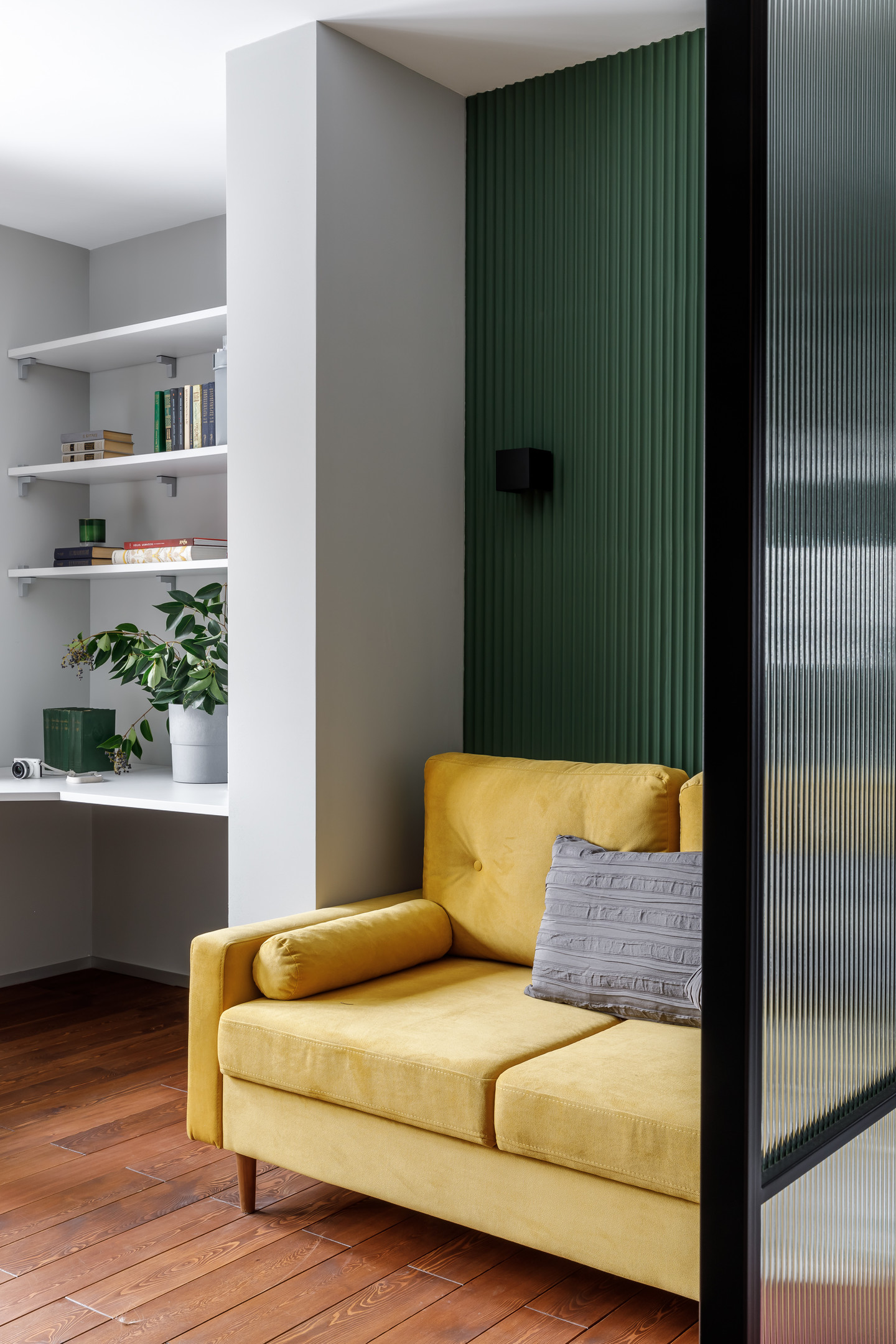 Phòng khách tuy nhỏ, chỉ chiếm một góc phòng nhưng vẫn nổi bật nhờ sự kết hợp của tường màu xanh lá với những đường kẻ sọc sinh động, thêm một chiếc ghế sofa màu vàng êm ái, loại bỏ bàn nước cho không gian thoáng đãng.