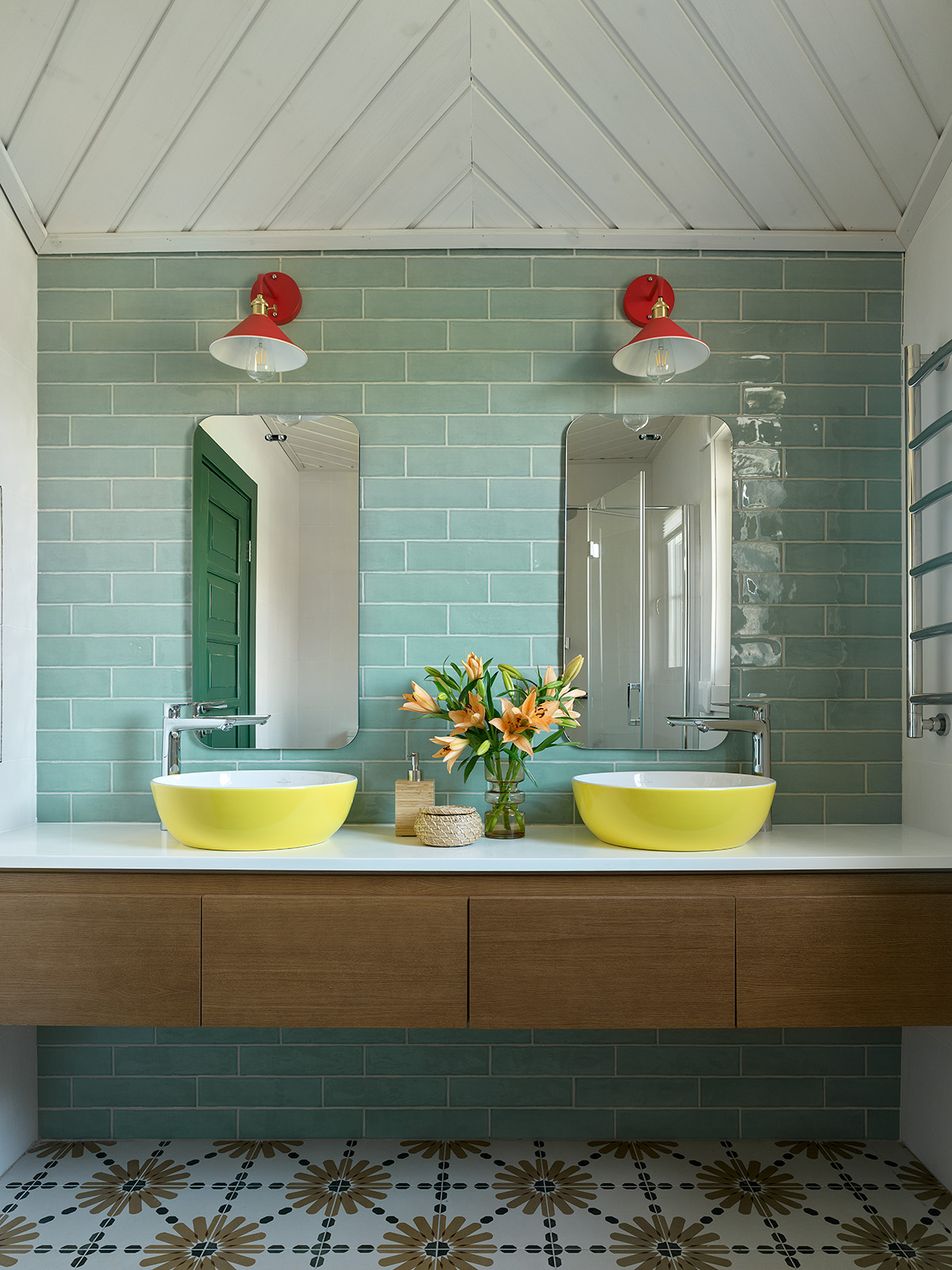 Phòng tắm này là sự kết hợp của màu xanh lá cây đậm cho cánh cửa ra vào được phản chiếu qua tấm gương, xanh ngọc cho gạch thẻ ốp tường sáng bóng và bồn rửa đôi màu vàng chanh cho vẻ đẹp trẻ trung hết nấc.