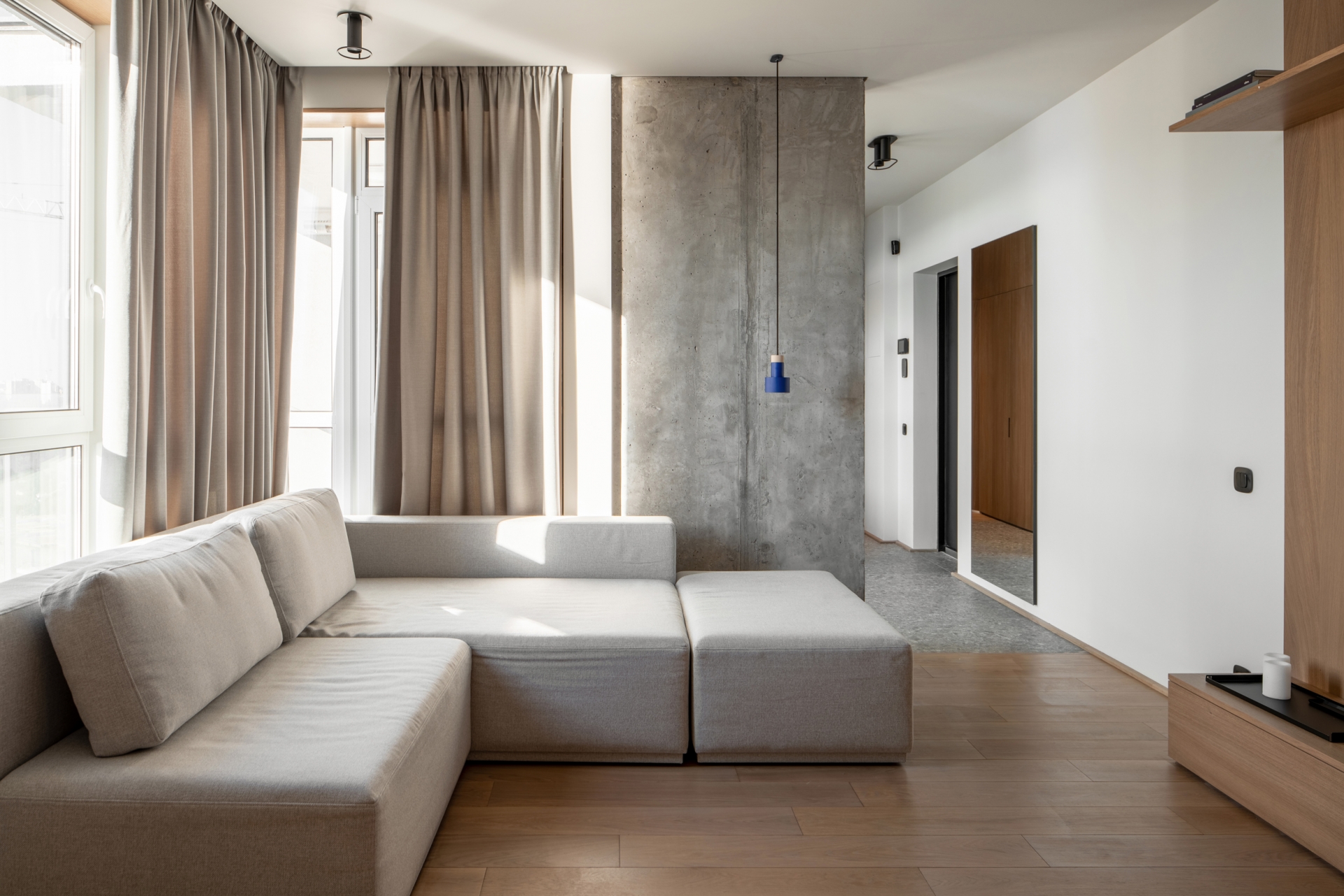 Về cơ bản, bê tông và gỗ dễ dàng kết hợp với các sắc màu nội thất khác nhau trong cùng một không gian. Ở đây, NTK đã tối giản cả về nội thất lẫn màu sắc với sofa module và rèm cửa màu be, loại bỏ bàn nước cho phòng khách giản dị nhất có thể. 
