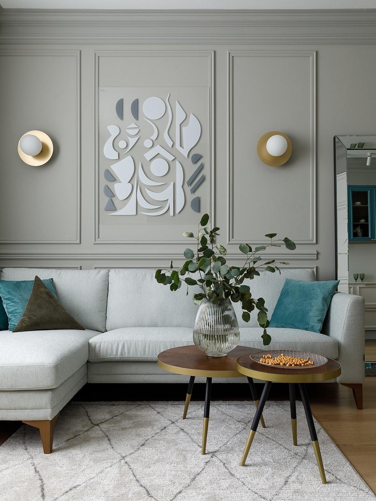 Phòng khách bố trí sofa kiểu module tiện ích, trang trí những chiếc gối tựa màu xanh lam. Bàn nước hình trong '2 trong 1' được trang trí bằng lọ thủy tinh xinh xắn. Trên bức tường, những mảnh gương nhỏ tạo nên một tác phẩm nghệ thuật độc đáo.