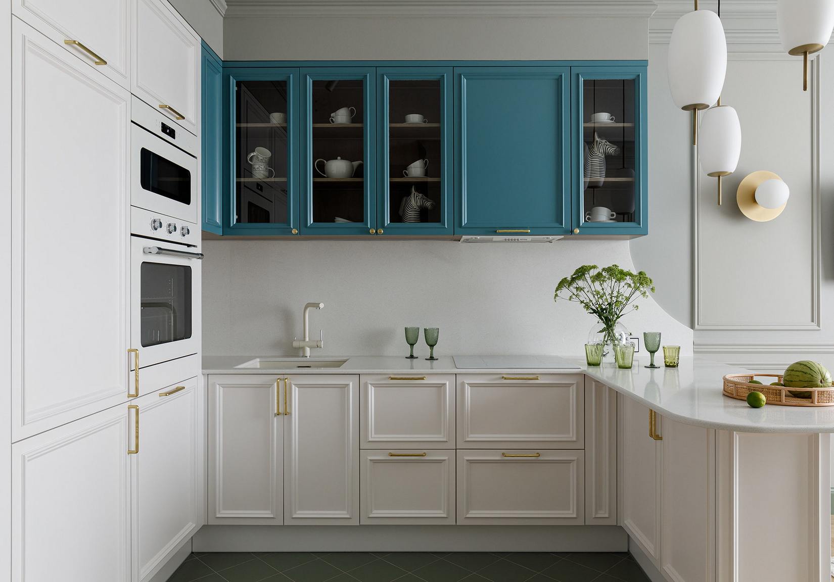 Nội thất phòng bếp được thiết kế với đường nét gọn gàng, hệ tủ lưu trữ bên dưới và nền tường màu trắng đối lập với tủ bếp trên chọn gam màu xanh thời thượng. Những chi tiết mạ vàng đồng ở tay nắm cửa tủ cũng nhấn nhá cho bếp thêm sang trọng.