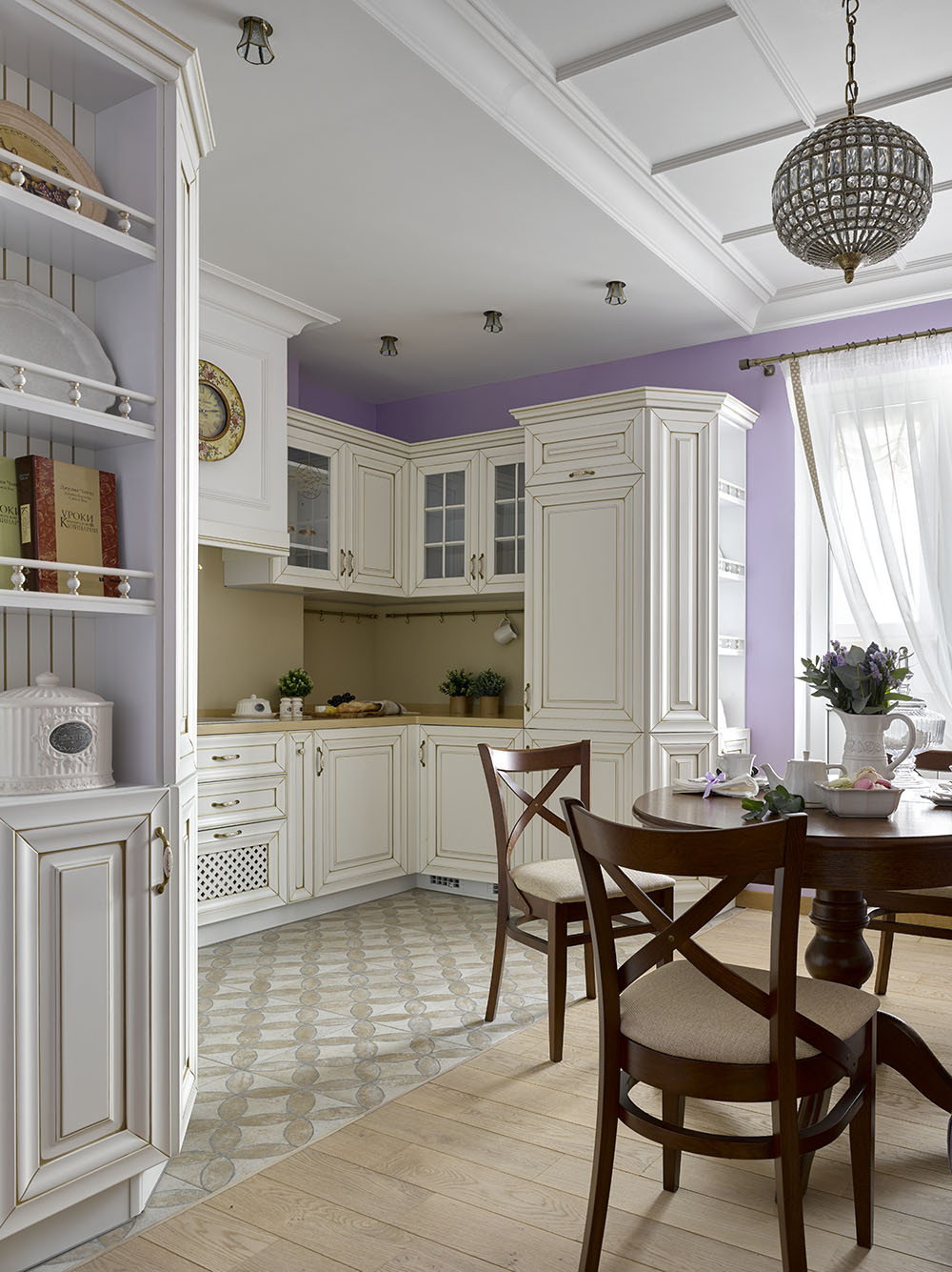 Không gian nấu nướng và ăn uống bố trí tại phòng riêng, phân vùng với nhau bằng gạch bông và gỗ lát sàn. Bếp kiểu chữ L với hệ tủ bếp màu trắng phong cách cổ điển.