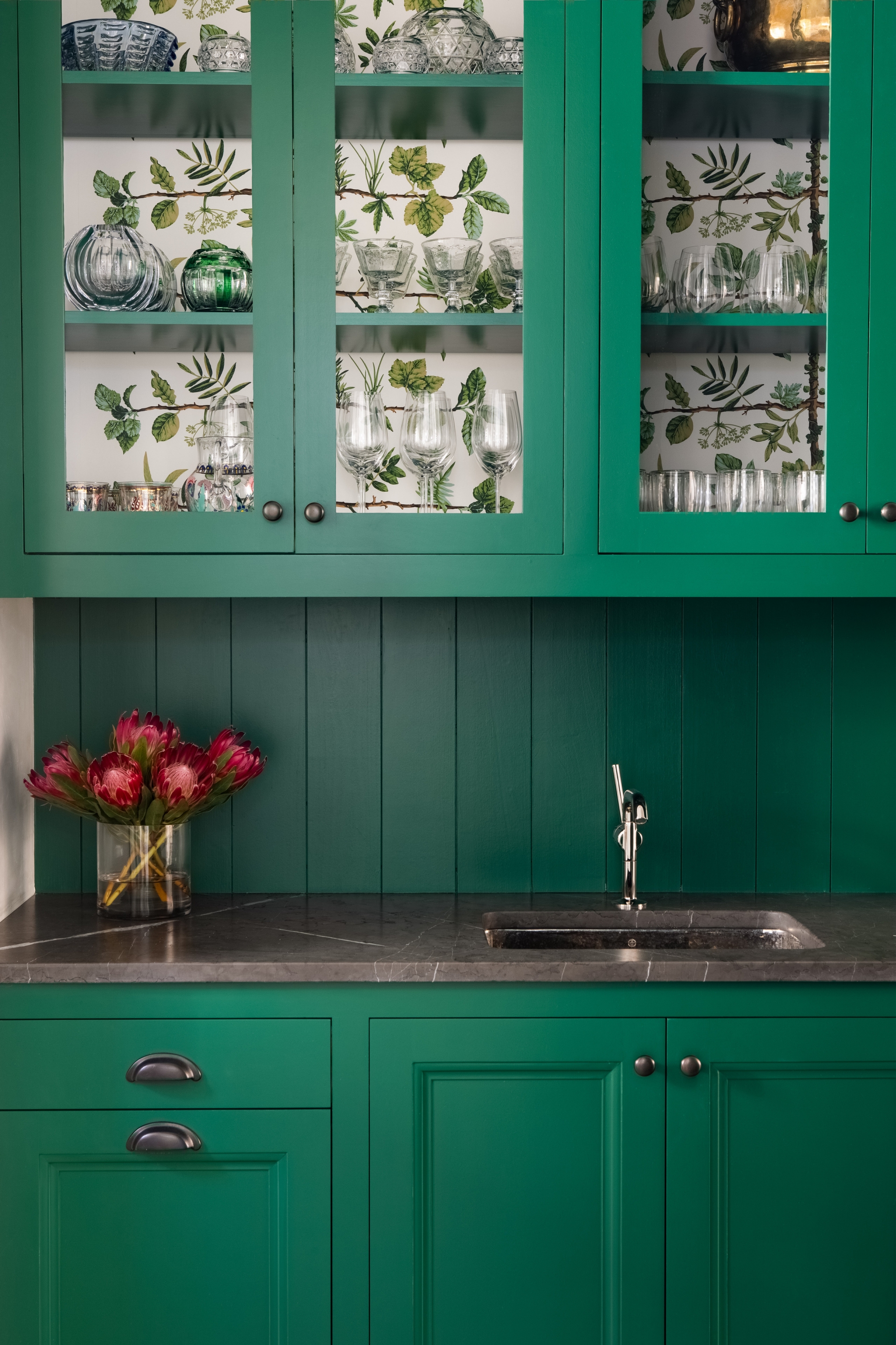Nếu bạn muốn thay áo mới cho phòng bếp một cách nhanh chóng mà không tốn nhiều thời gian thì hãy sơn tủ bếp màu xanh ngọc lục bảo, đồng thời sử dụng giấy dán tường hoa lá xinh xinh lót phía trong tủ cửa kính như hình minh họa.