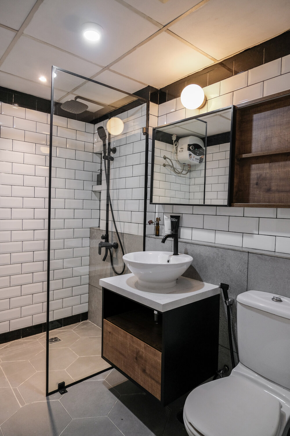 Phòng tắm là sự kết hợp của gạch hình lục giác lát sàn với gạch thẻ metro ốp tường tương tự backsplash. Tủ lưu trữ kết hợp gương soi tiện ích trên bồn rửa, cửa kính trong suốt giúp phân vùng buồng tắm và toilet mà vẫn tạo cảm giác rộng rãi. 