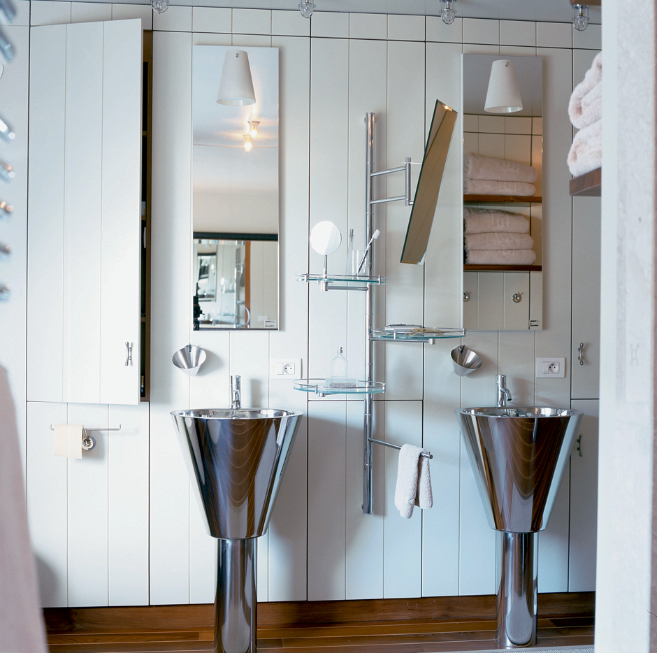 Có rất nhiều các giải pháp lưu trữ được áp dụng, bao gồm tủ lưu trữ sơn trắng như bức tường sau bồn rửa đôi, kệ mở sắp xếp khăn tắm phía đối diện được phản chiếu qua tấm gương, đặc biệt là giá treo gắn tường mặt kính trong suốt ở vị trí trung tâm.