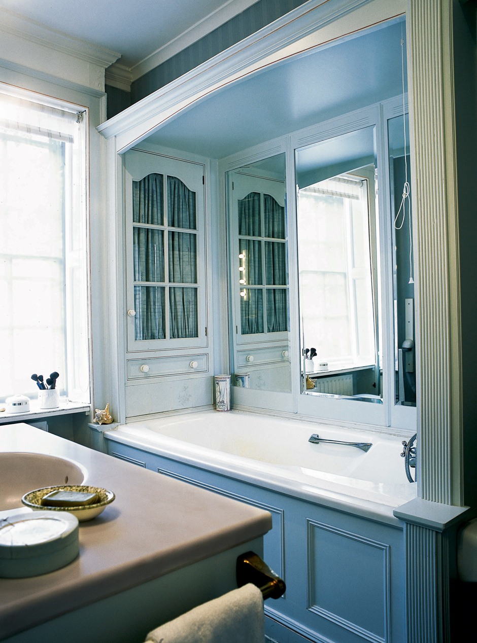 Không gian mát rượi với gam màu xanh lam dịu dàng như biển cả. Bức tường phía trên bồn tắm nằm được lắp đặt tủ lưu trữ kiểu cổ điển gọn gàng, thêm vào tấm gương lớn ở bức tường cho không gian rộng hơn nhờ thị giác. 