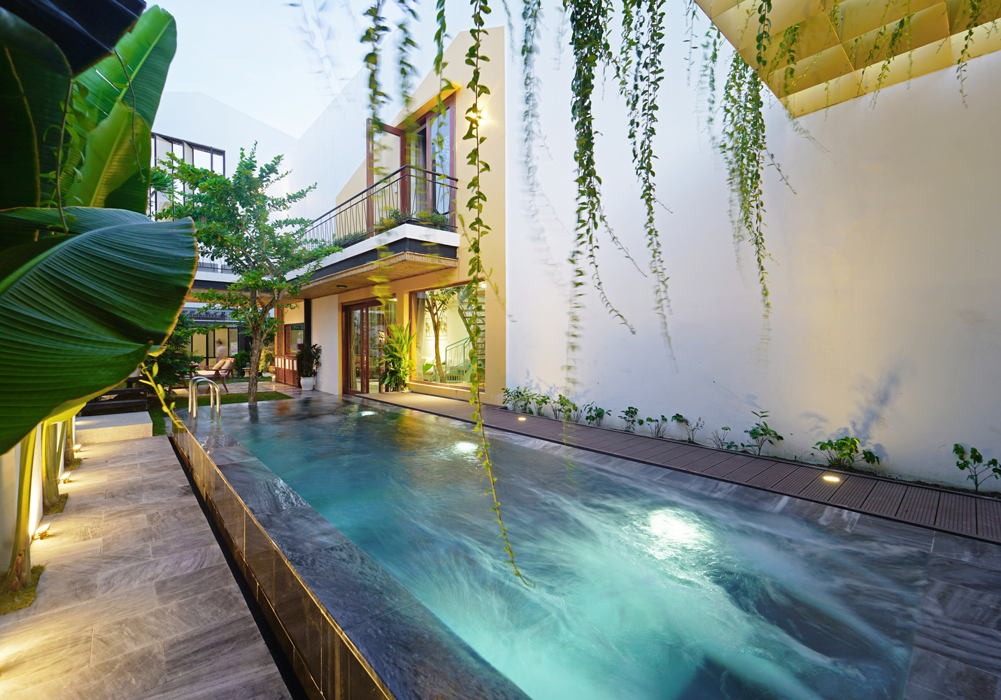 Bên cạnh những ưu điểm trên thì ngôi nhà còn tạo được điểm nhấn nhờ thiết kế hồ bơi trải dài bên hông nhà, lát đá xanh lam mát rượi. 